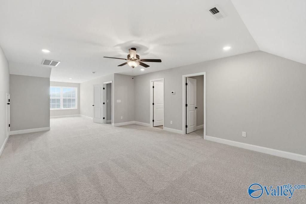 Spacious bonus room with plush carpeting and ceiling fan in The Rockford floor plan at Cain Park, Hartselle, Alabama.