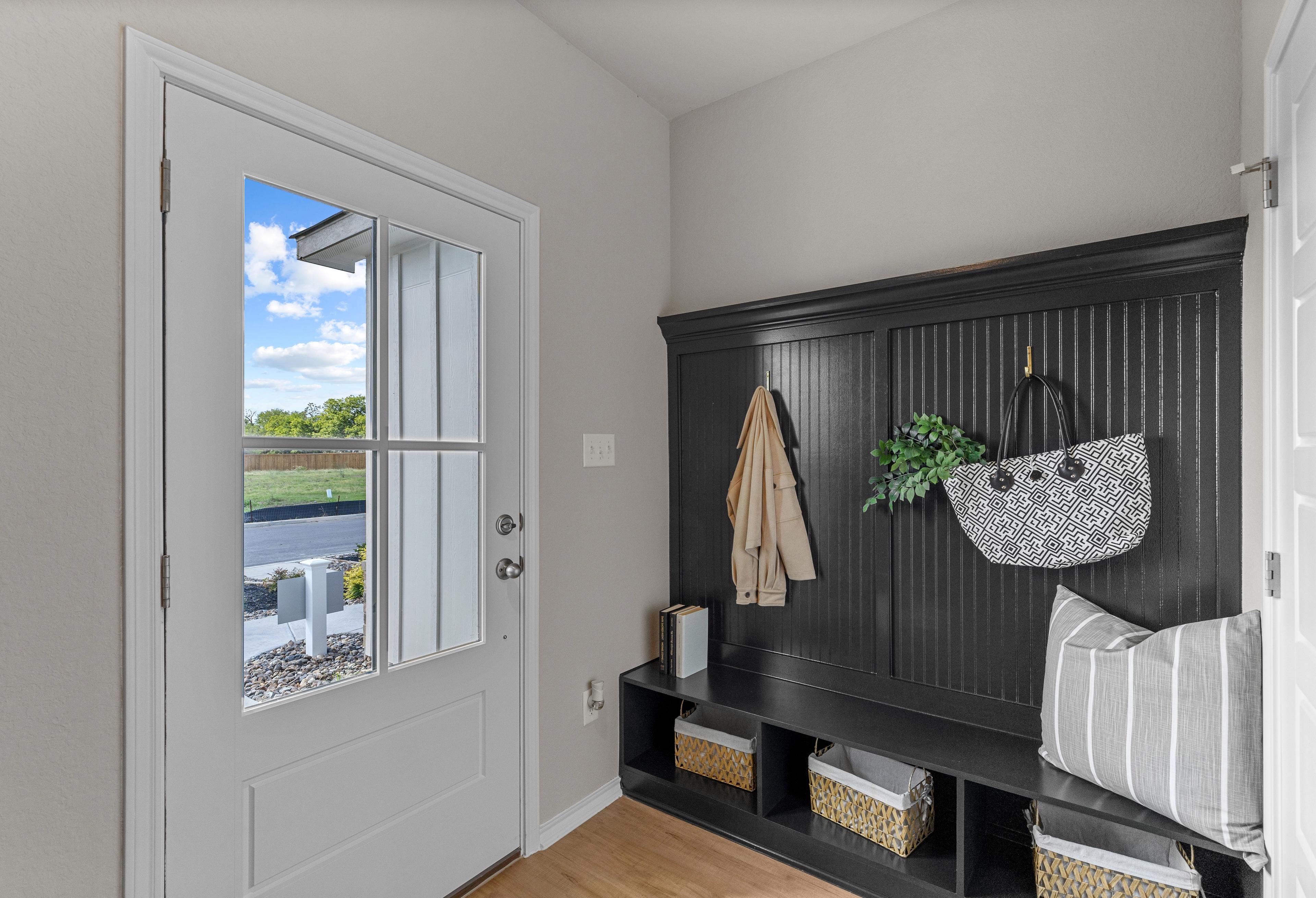 Inviting mudroom in The Sabine A Davidson Homes design featuring black built-in cabinetry, coat hooks, storage baskets, and backyard view