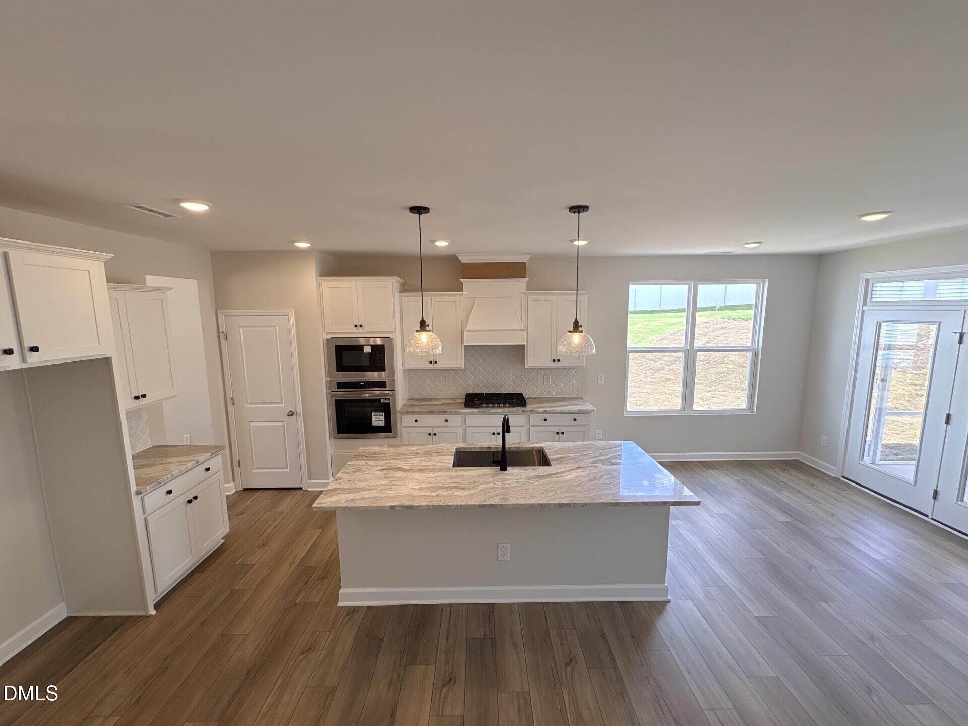 Modern kitchen with granite island and white cabinets in The Ash C floor plan at Woodland Crossing, Zebulon, North Carolina.