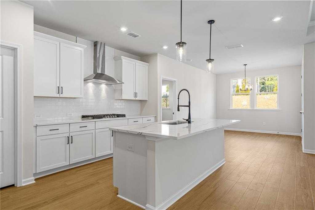 Modern white kitchen with large island, stainless range hood, subway tile backsplash in Davidson Homes Edison A, Loganville GA