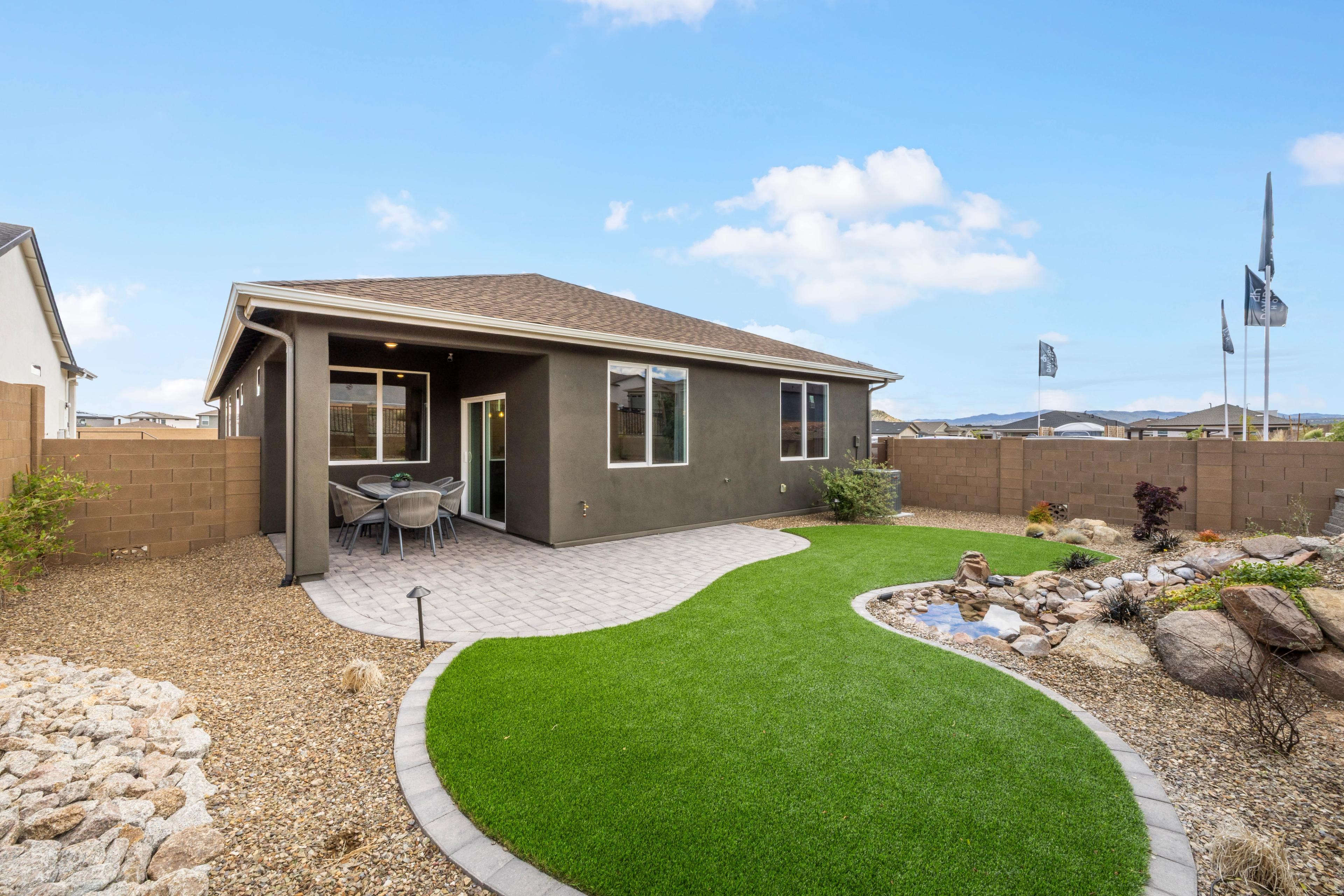Covered patio with outdoor seating and curved artificial turf at South Ranch in Prescott AZ, rock garden pond and desert landscaping