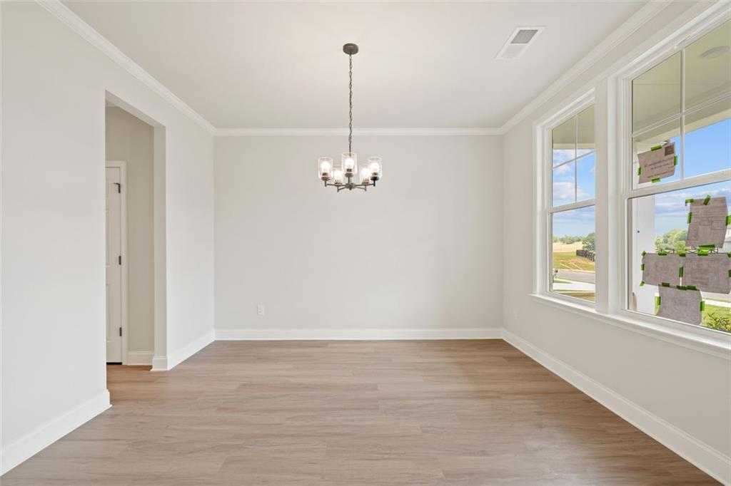Elegant dining room with crystal chandelier, large windows, and hardwood floors in Davidson Homes The Ash B at Wehunt Meadows, Hoschton, GA