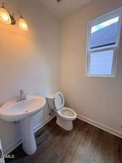 Half bathroom with pedestal sink and wood-style flooring in The Willow B floor plan at Woodland Crossing, Zebulon, NC.