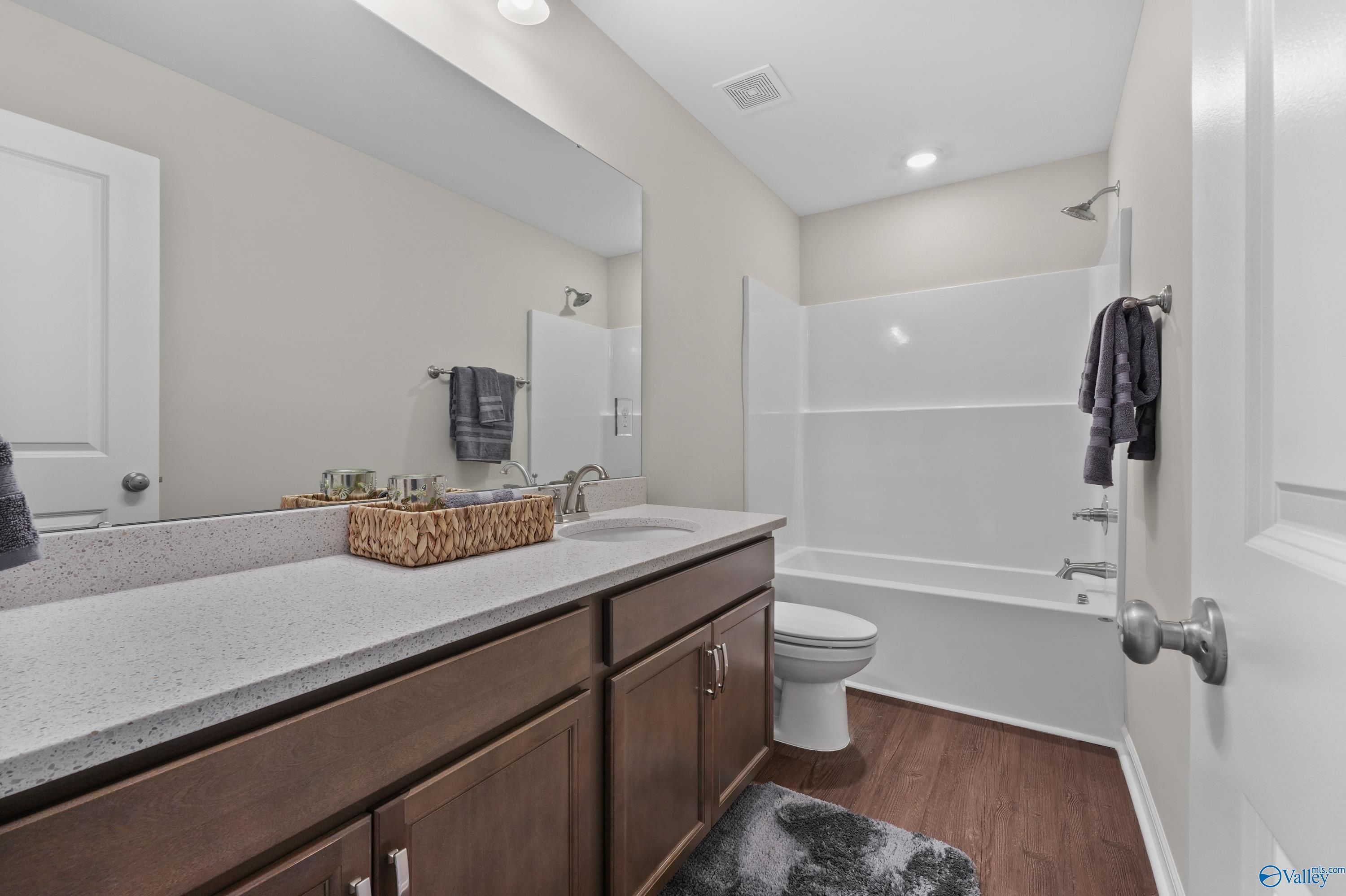 Modern master bathroom featuring double granite vanity, deep tub, glass shower, and wood floors in The Stella by Davidson Homes, Hazel Green, AL