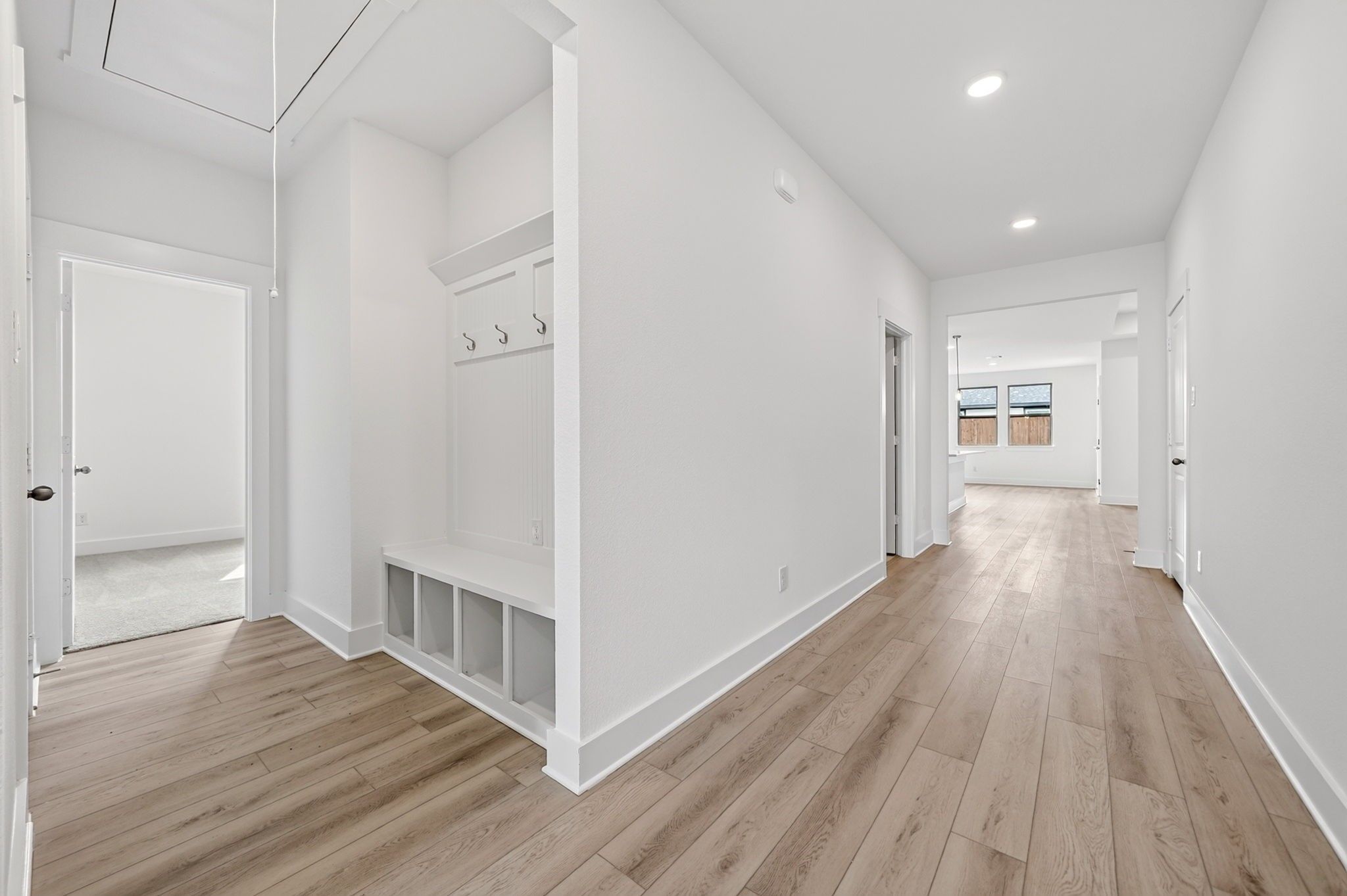 Bright entryway with mudroom bench, coat hooks, and luxury vinyl plank flooring in Davidson Homes Holly F plan, Josephine, TX