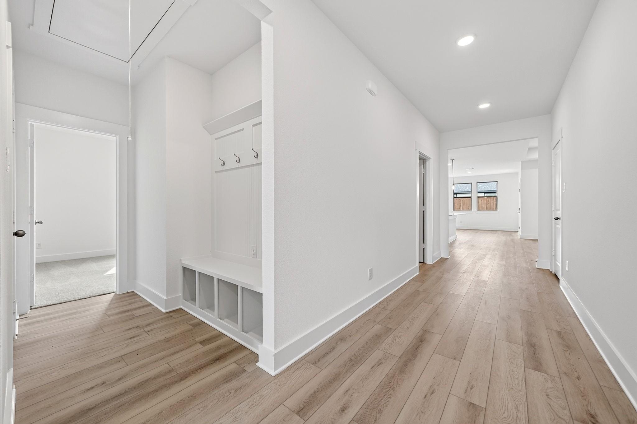 Bright entryway with mudroom bench, coat hooks, and luxury vinyl plank flooring in Davidson Homes Holly F plan, Josephine, TX
