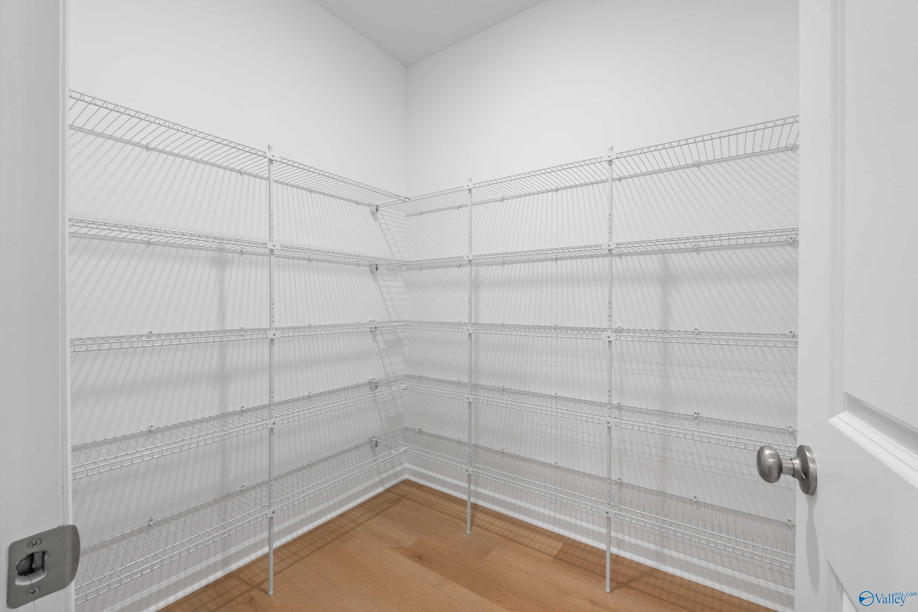 Spacious corner walk-in pantry with white wire shelving in Davidson Homes The Luna, Hazel Green, Alabama