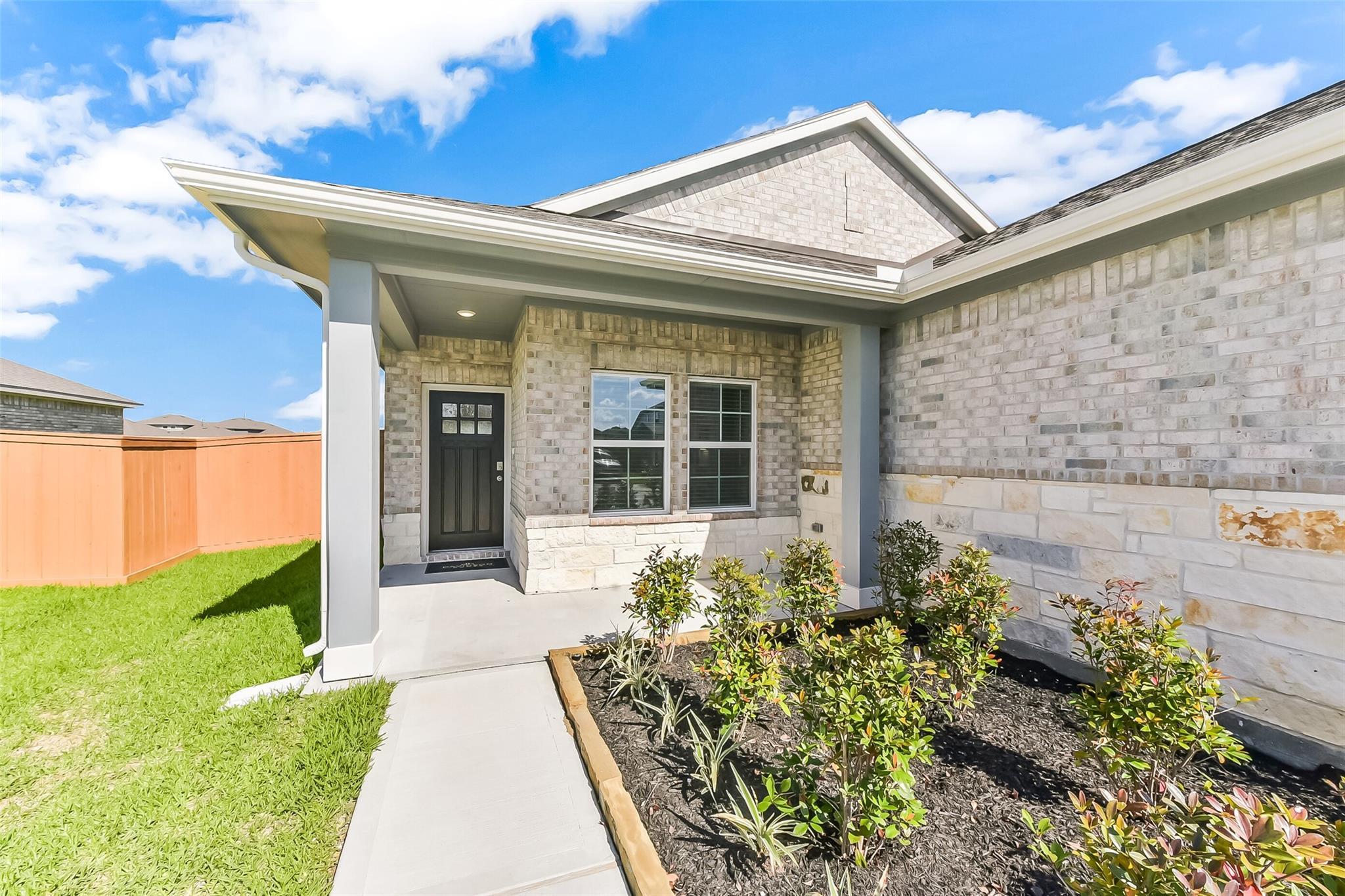 Modern brick exterior of Davidson Homes The Costa C with covered porch, front door, windows, and landscaped front yard in Dayton, Texas