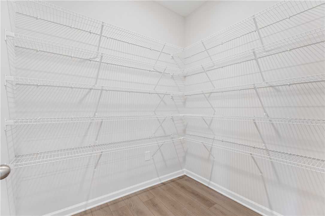 Spacious walk-in closet featuring white wire shelving and hardwood floors in Davidson Homes The Luna B, Opelika, Alabama