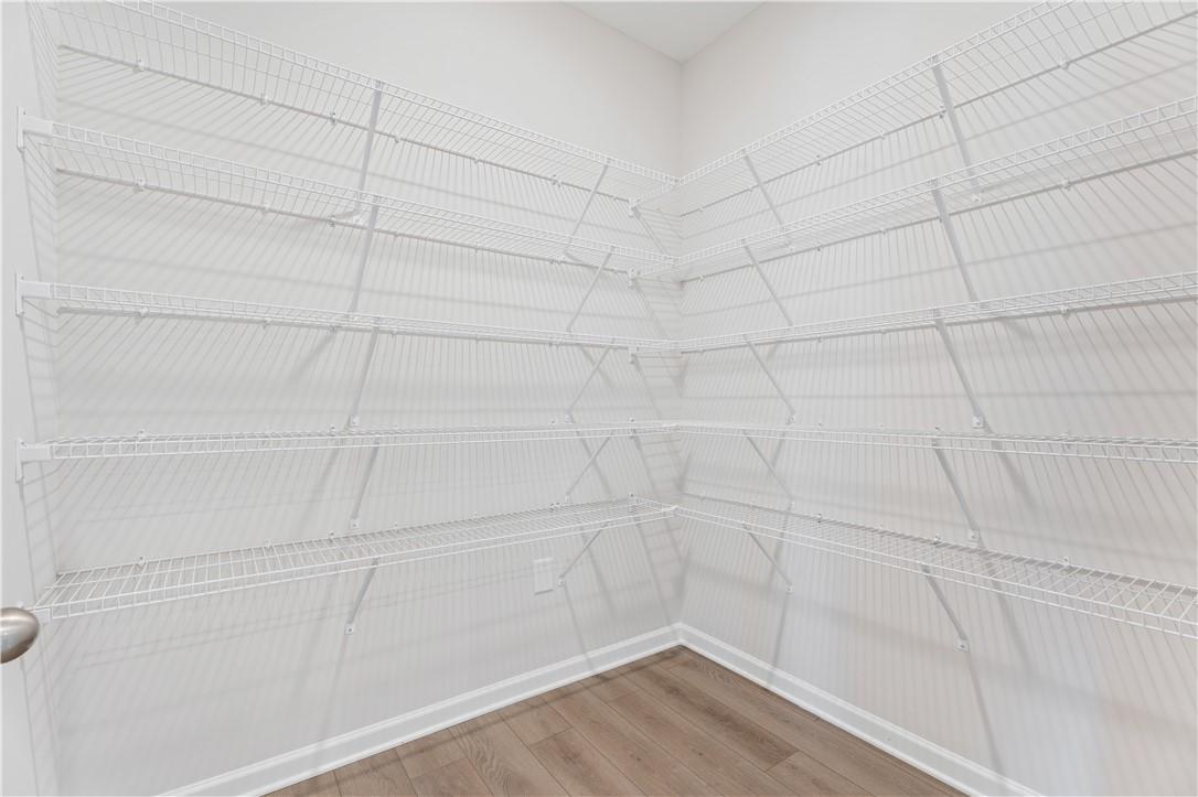 Spacious walk-in closet featuring white wire shelving and hardwood floors in Davidson Homes The Luna B, Opelika, Alabama