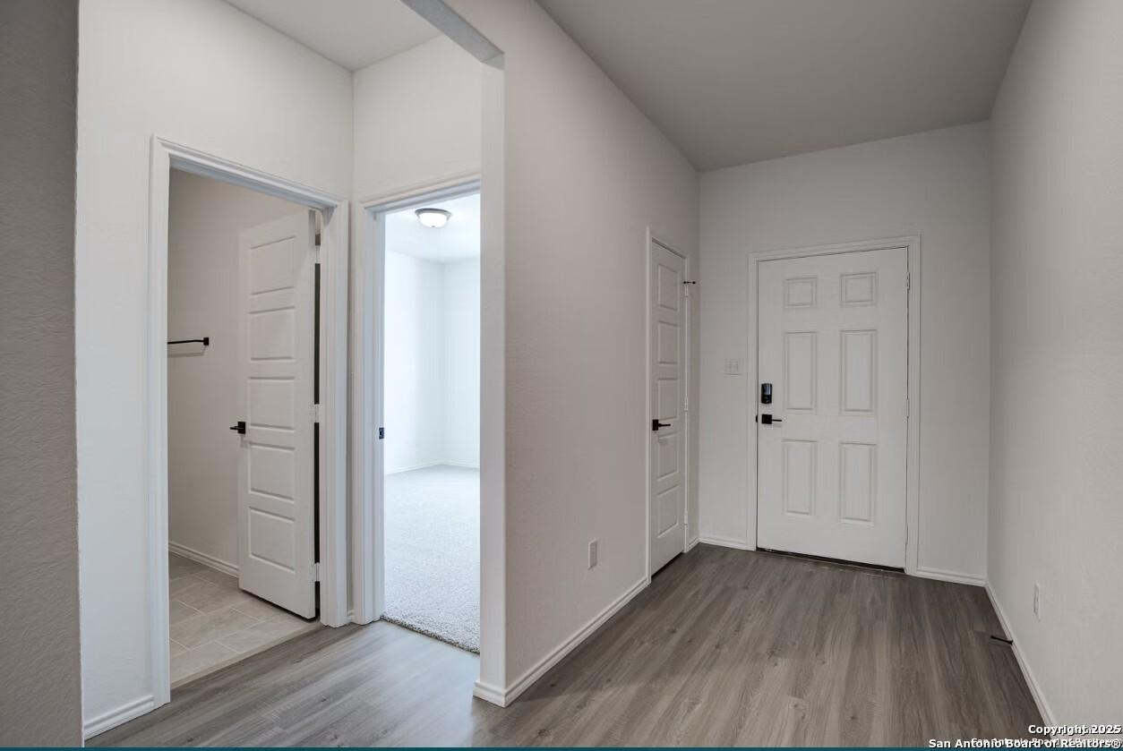 Bright hallway with open doors to master bathroom and bedroom, gray laminate floors in Davidson Homes The Daphne H, Seguin, Texas