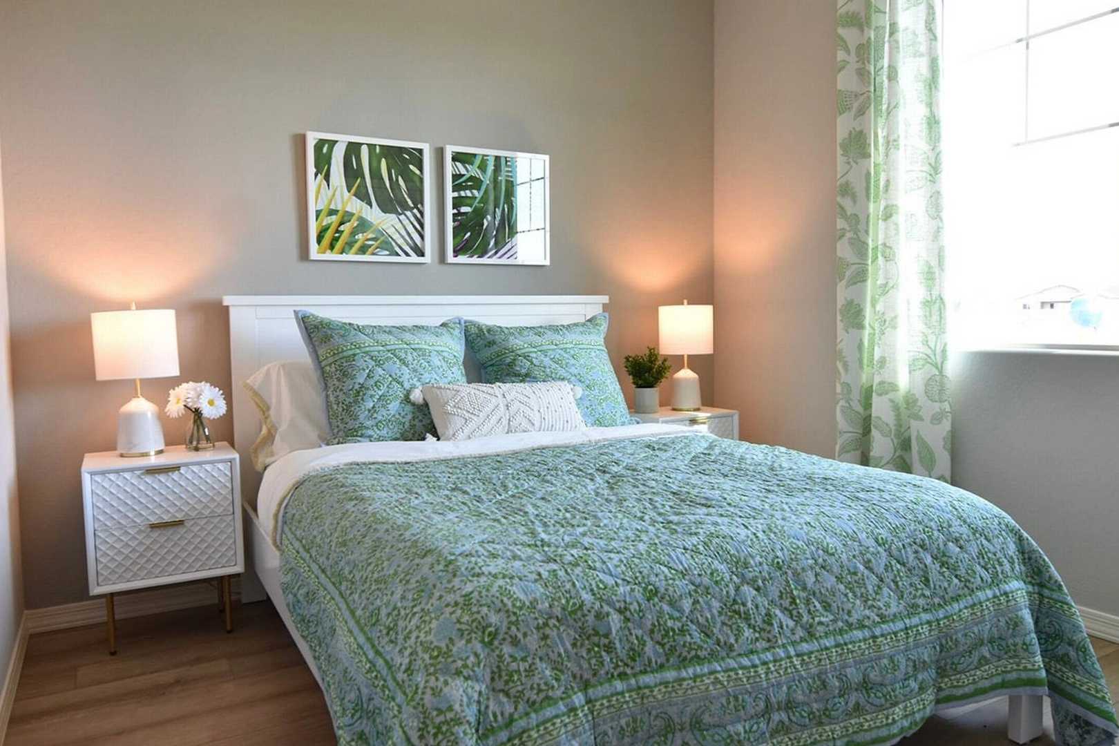 Cozy bedroom at North Ridge Pronghorn Ranch in Prescott Valley AZ with teal bedding, palm leaf art, and green curtains