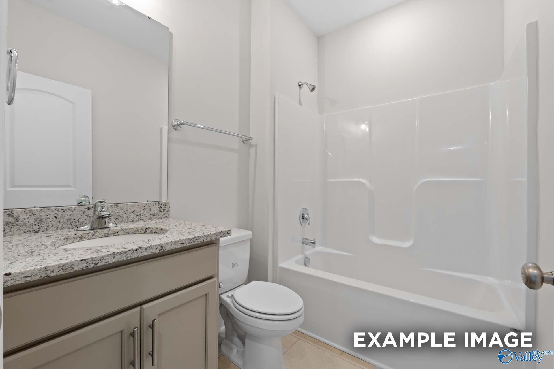 Full bathroom with granite vanity and tub-shower combo in The Madison A floor plan by Davidson Homes in Toney, Alabama.