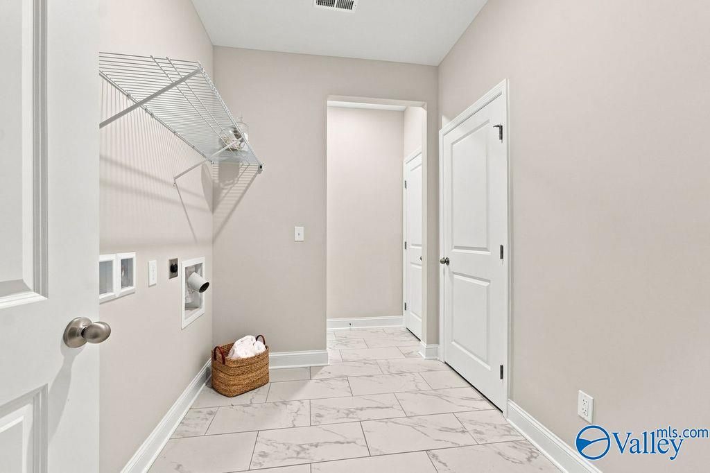 Laundry room with wire shelving, tile flooring, and wicker basket in Davidson Homes The Harrison, Cain Park, Hartselle, Alabama