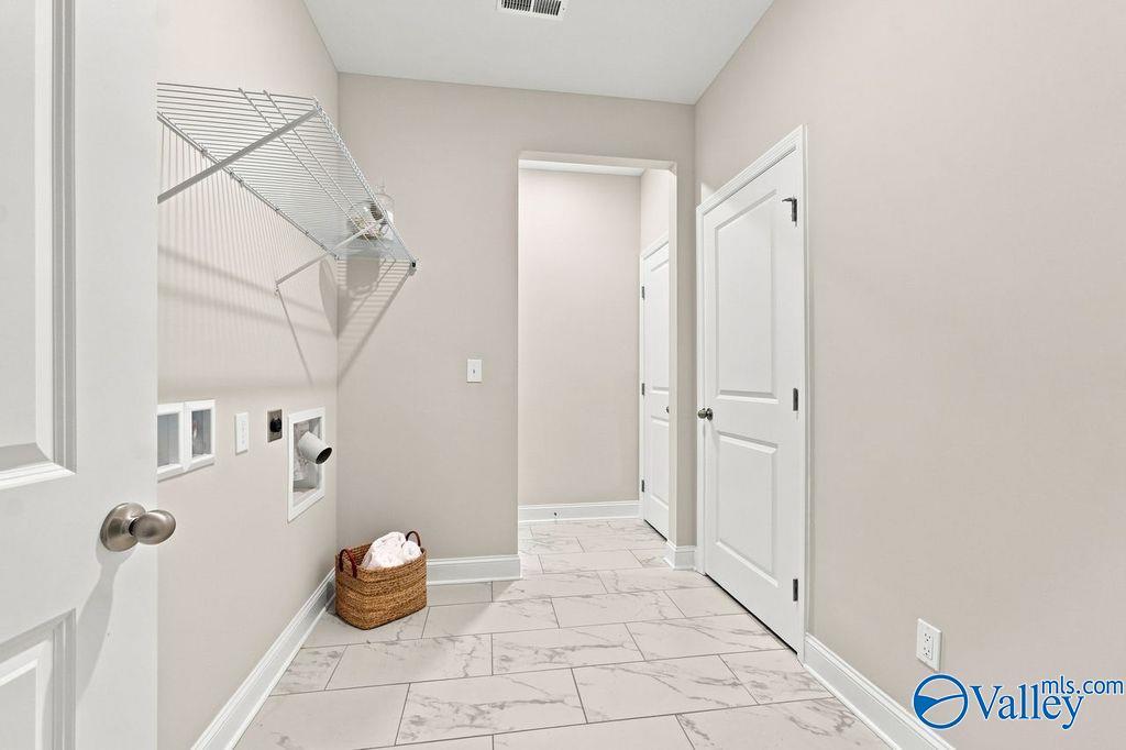 Laundry room with wire shelving, tile flooring, and wicker basket in Davidson Homes The Harrison, Cain Park, Hartselle, Alabama