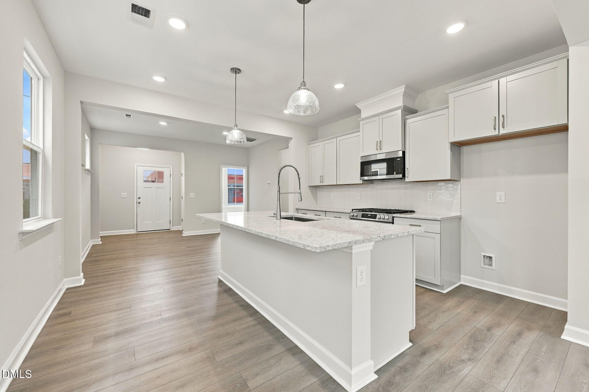 Bright open-concept kitchen with white cabinetry, granite island, and stainless appliances in Davidson Homes' The Alexander B, Knightdale NC