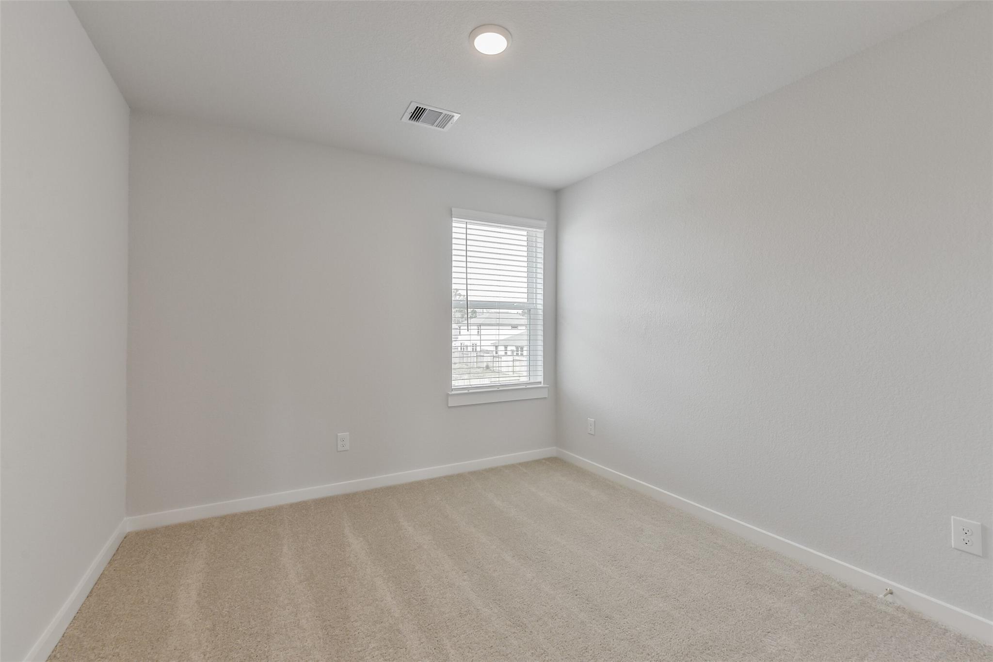 Empty secondary bedroom with beige carpet, light gray walls, and window blinds in Davidson Homes The Brazos E, Cleveland, Texas