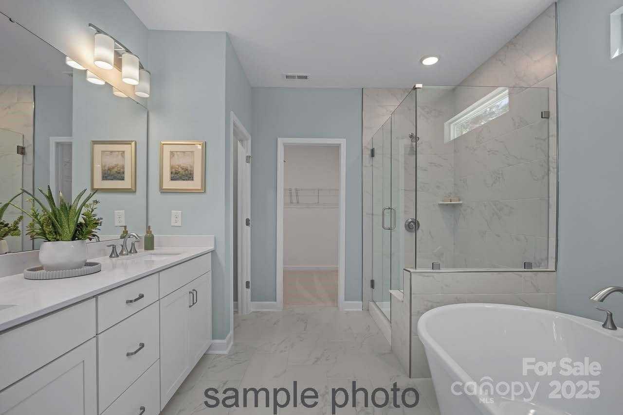 Luxurious master bathroom featuring freestanding tub, frameless glass shower, white double vanity in Davidson Homes Hickory E II, Belmont NC