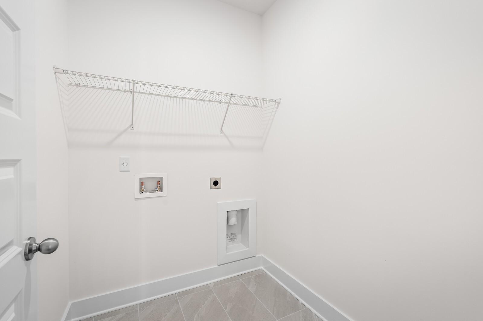 Laundry room with wire shelving and utility hookups in The Cottonwood E floor plan at Woods Crossing in Gallatin, TN.