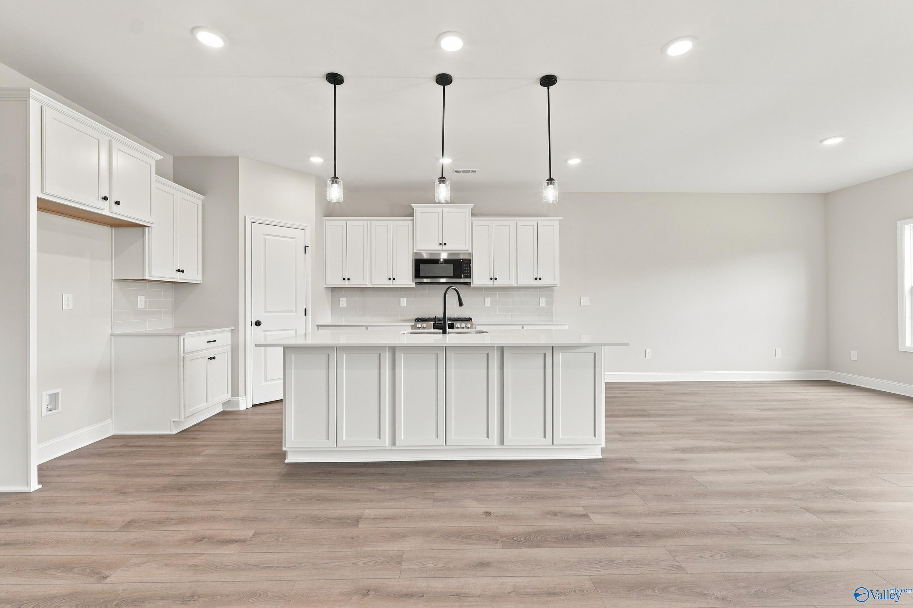 Modern kitchen with white cabinets, island, and pendant lighting in The Rockford B floor plan at Kendall Downs, Toney, AL.
