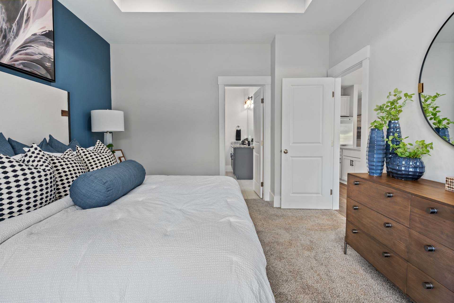 Master bedroom in Blue Spring Huntsville AL with navy accent wall, white king bed, blue pillows and en-suite bathroom