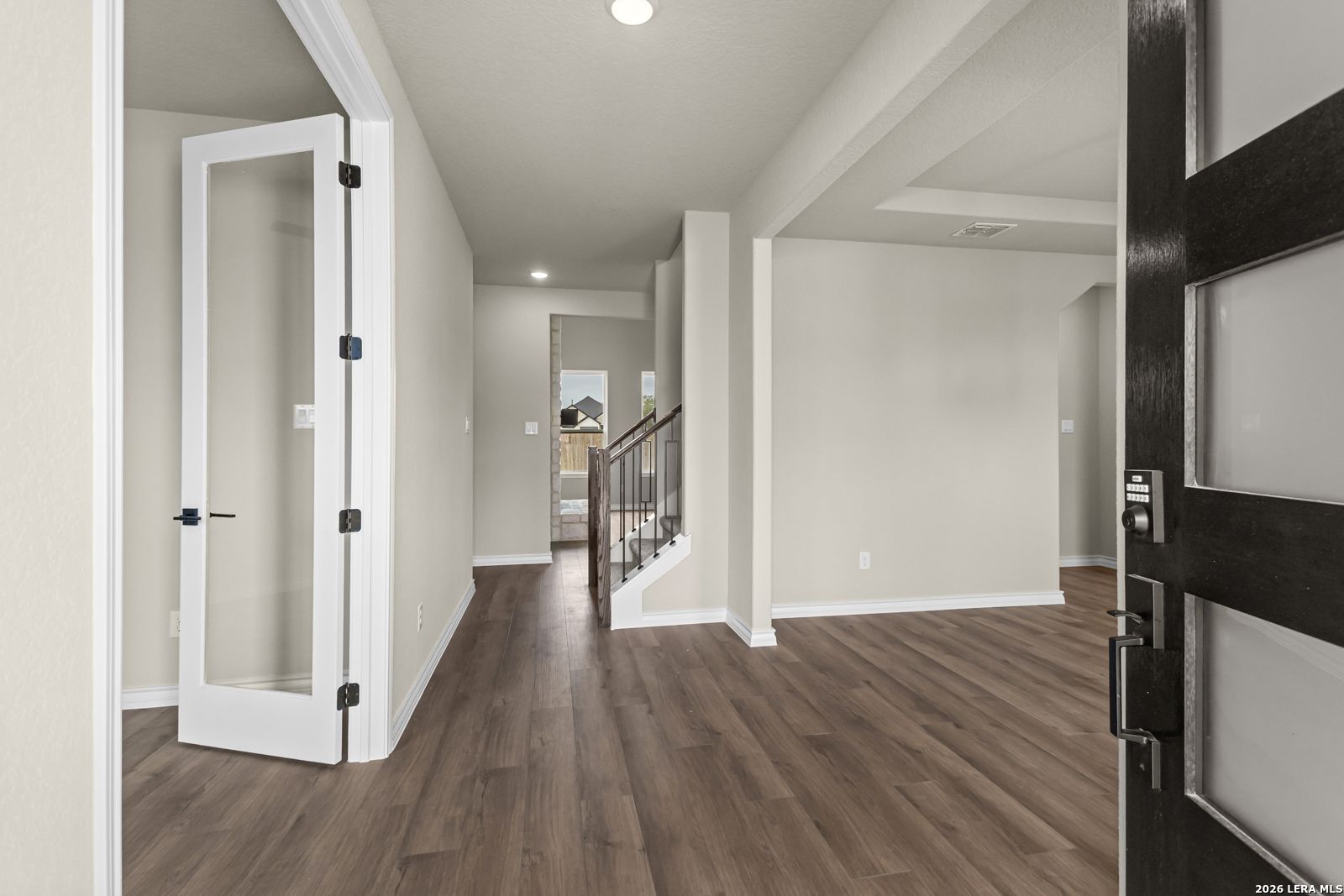 Bright entryway with wood-style flooring and glass-paneled door in The Danbury H model home at Potranco Oaks, Castroville.
