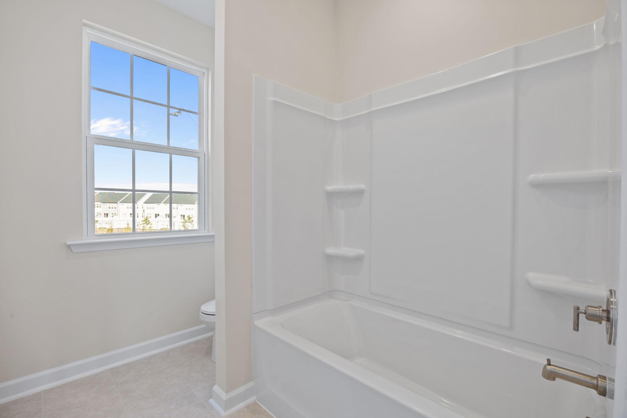 Modern bathroom with shower-tub combo at Forestville Yard in Knightdale, NC by Davidson Homes