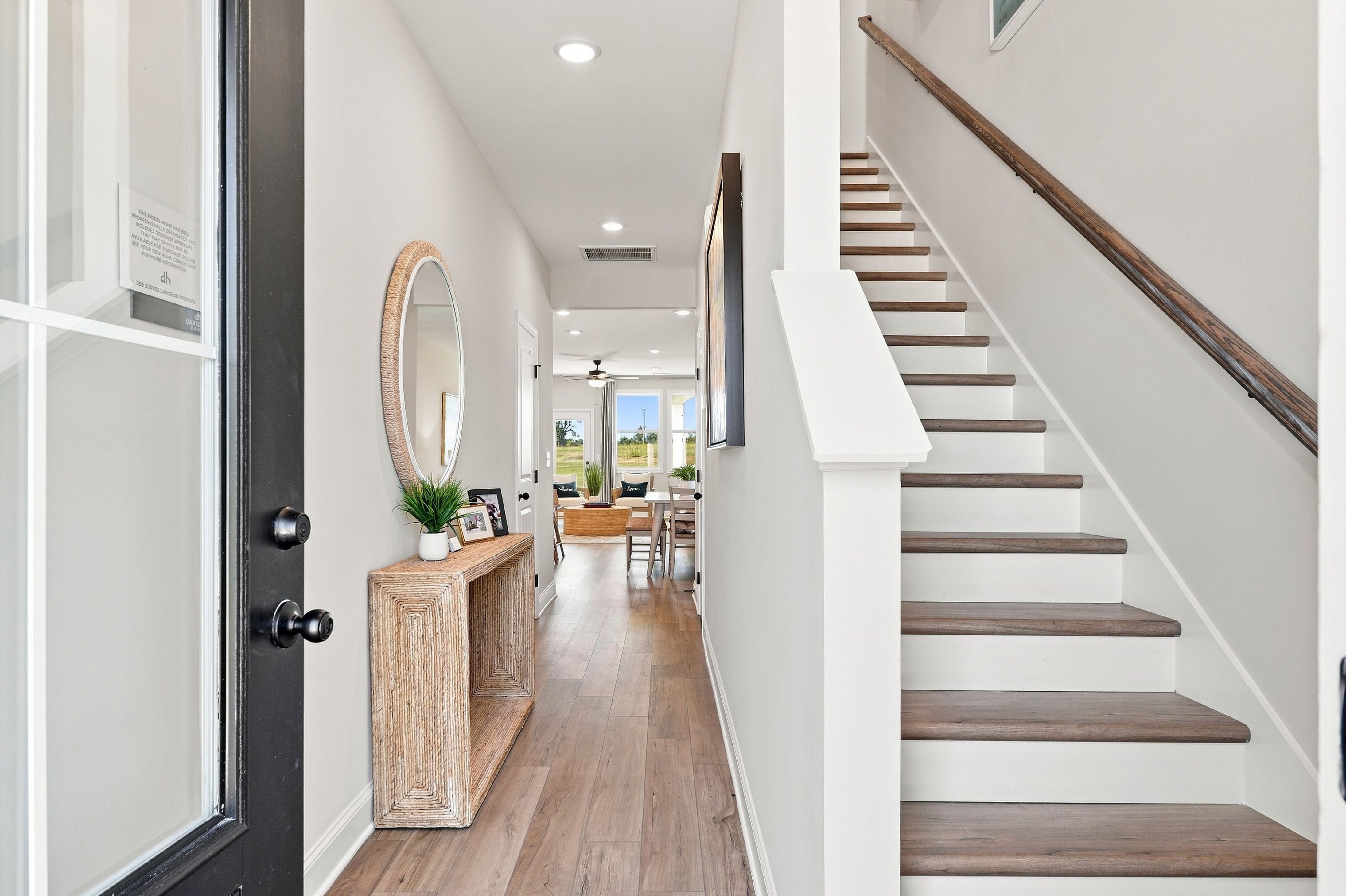 Bright foyer with wood-look flooring, wooden staircase, and console table at Bailey Park by Davidson Homes in Fayetteville, TN