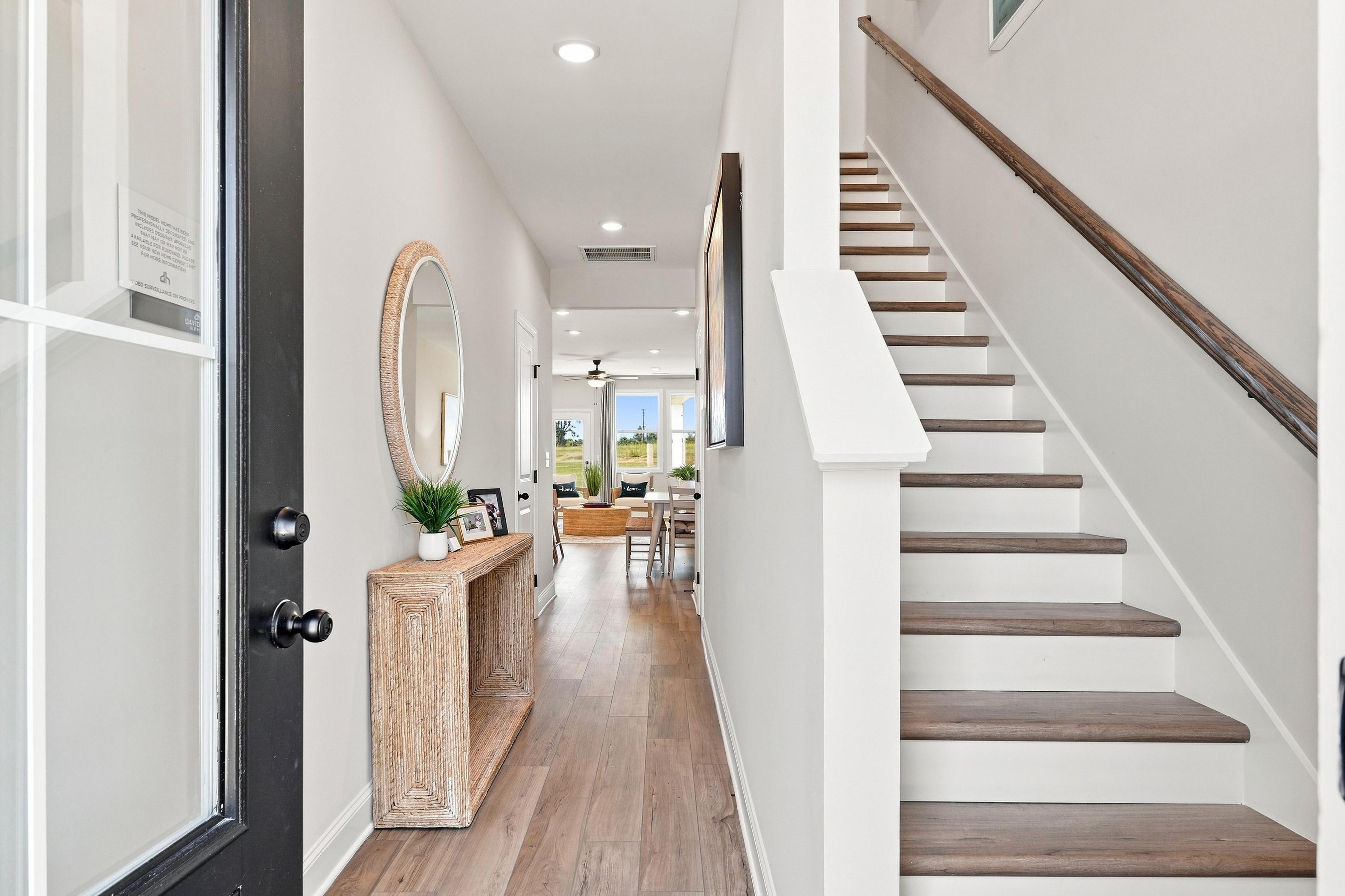 Bright foyer with wood-look flooring, wooden staircase, and console table at Bailey Park by Davidson Homes in Fayetteville, TN
