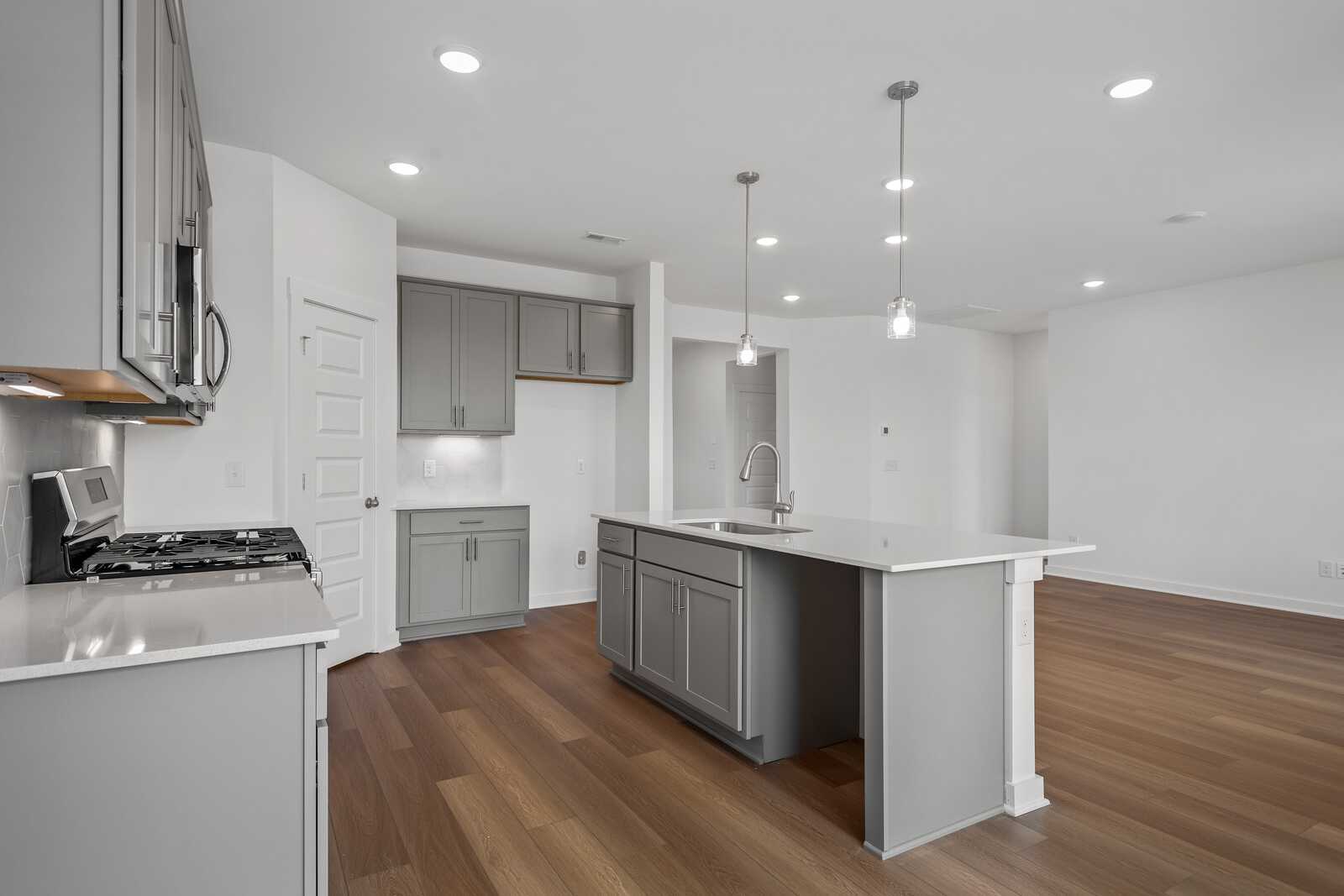 Spacious modern kitchen in The Asheville featuring gray shaker cabinets, white quartz island, and open layout