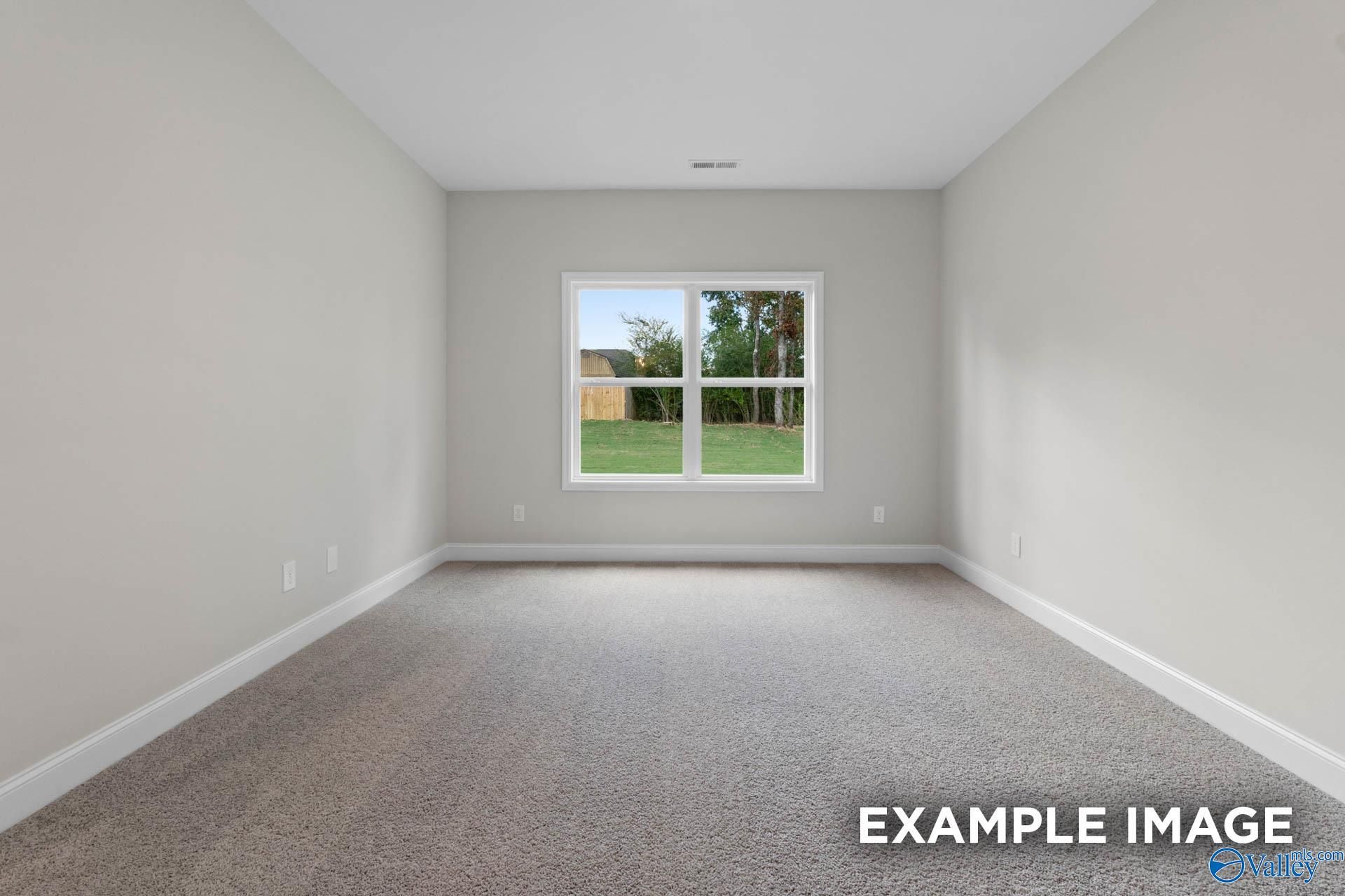Spacious empty bedroom with large window overlooking treed backyard in Davidson Homes The Franklin V, Athens, Alabama