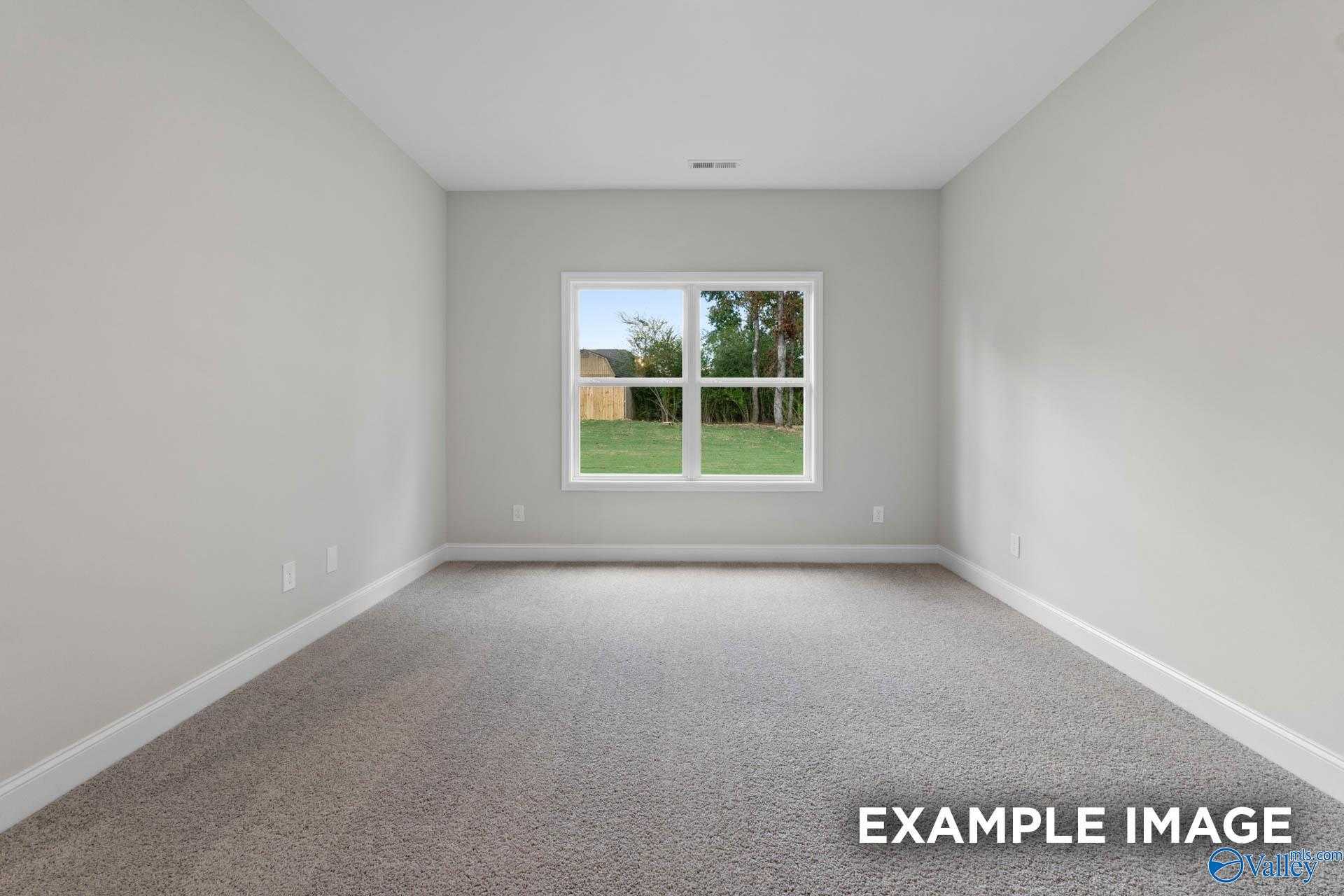 Spacious empty bedroom with large window overlooking treed backyard in Davidson Homes The Franklin V, Athens, Alabama