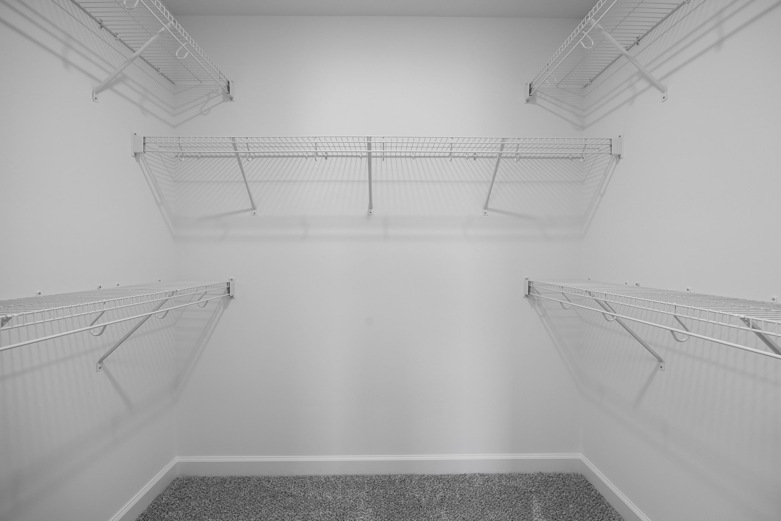 Spacious walk-in closet in The Magnolia B master suite with wire shelving, white walls, and gray carpet floor