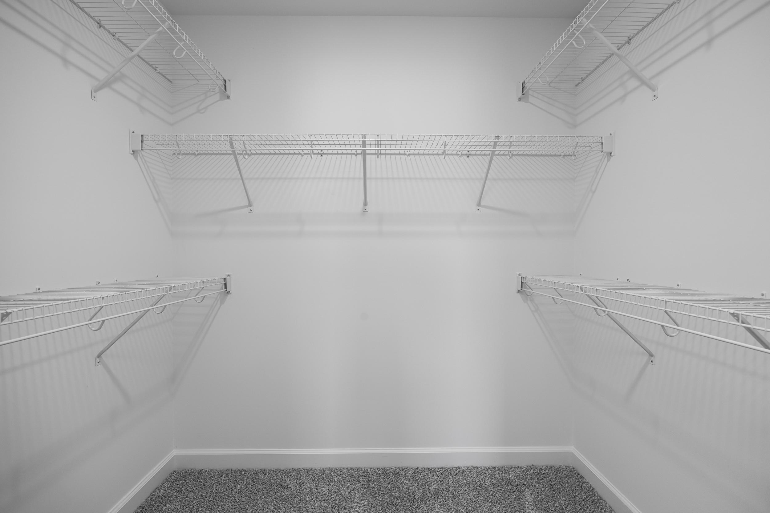 Spacious walk-in closet in The Magnolia A master suite featuring white wire shelving and gray carpet floor
