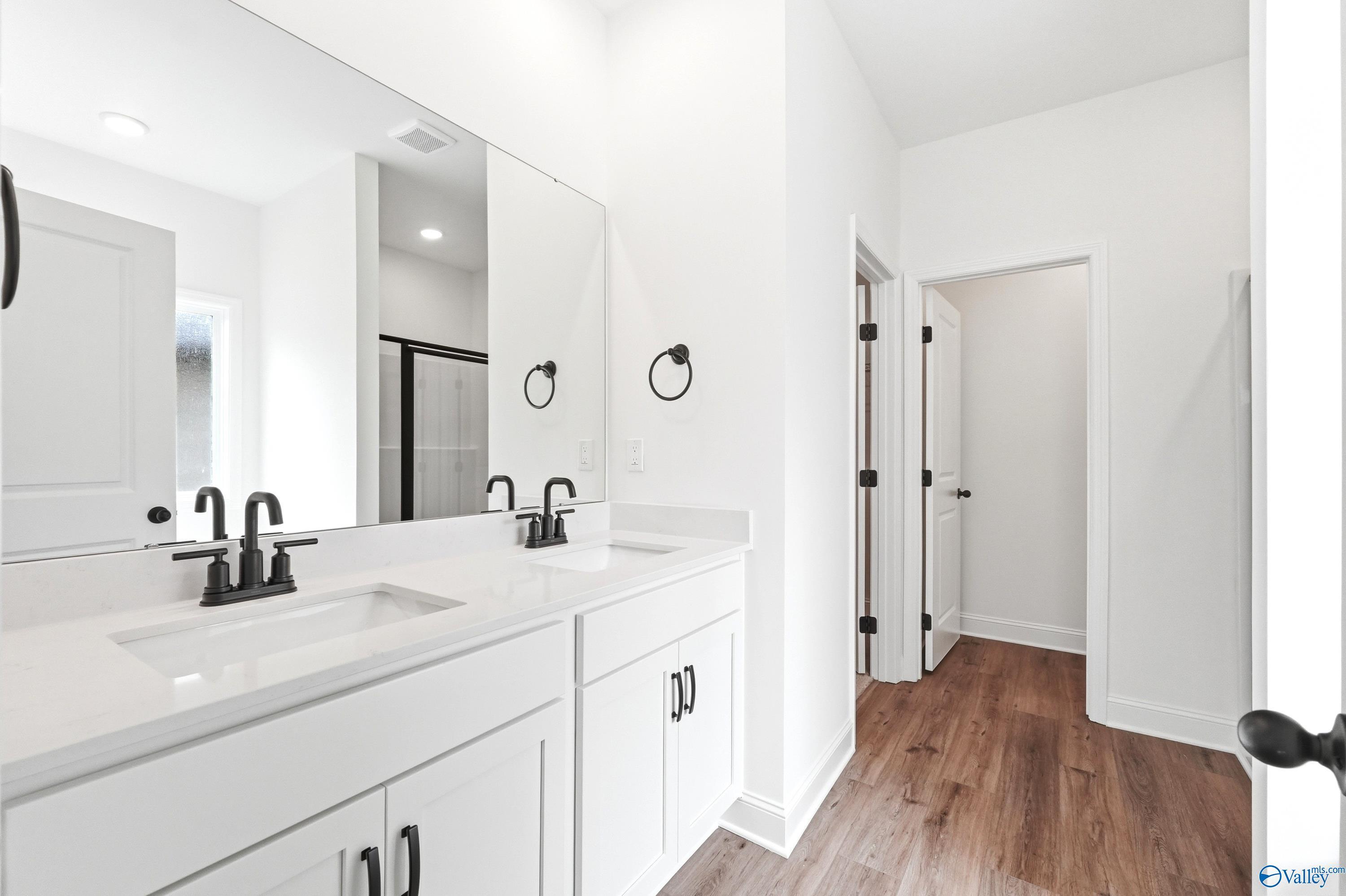 Modern double-vanity bathroom with white cabinets and black fixtures in The Daphne C home at Ivy Hills, Toney, Alabama.
