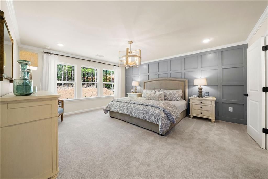 Serene master bedroom with king bed, gray board-and-batten wall, chandelier, and large windows in Davidson Homes The Willow B, Riverwood, Dallas, GA