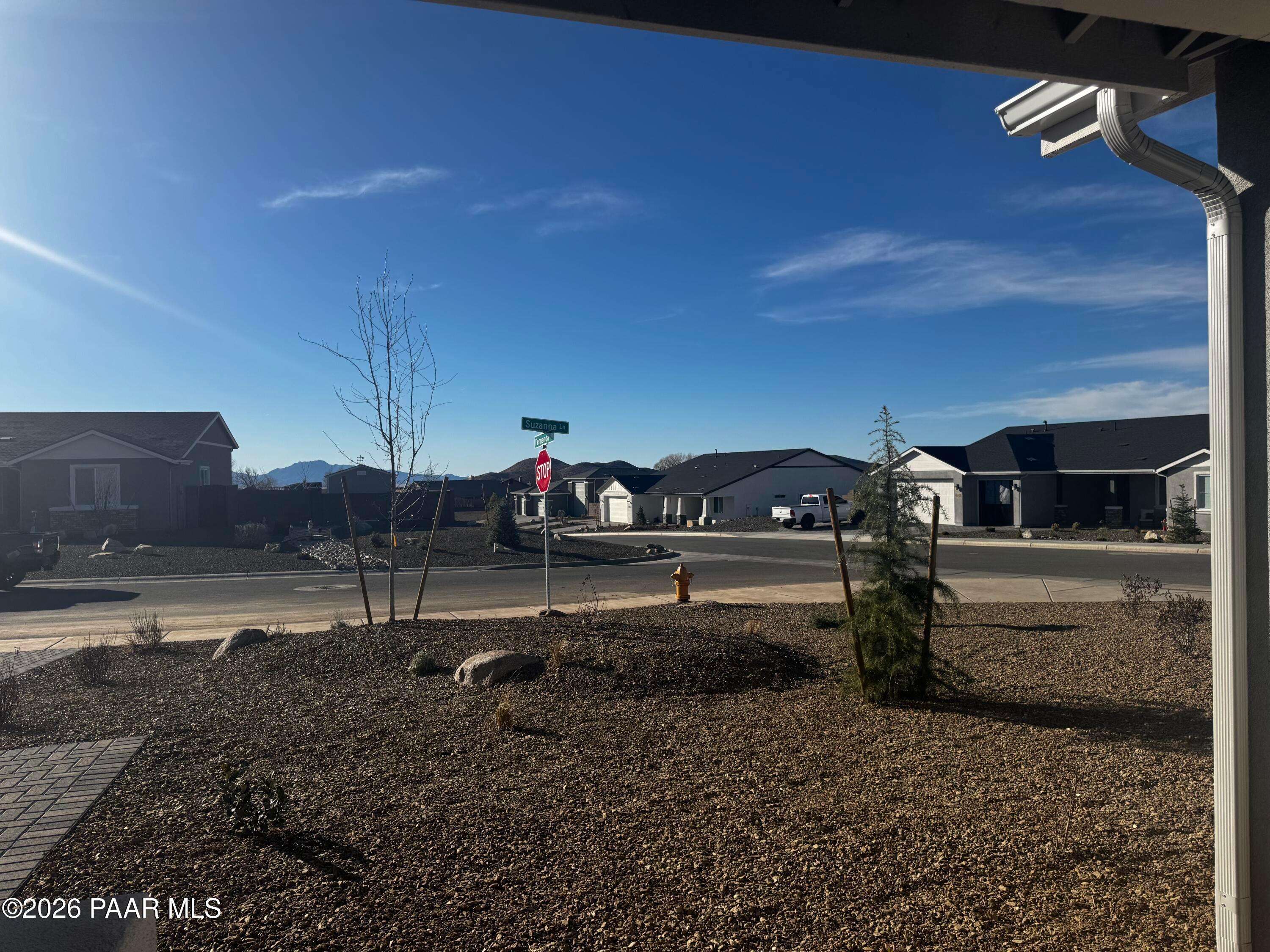 Scenic Morningstar neighborhood view from The Monarch B home in Prescott Valley, Arizona, with single-story houses, desert gravel landscaping, and mountain backdrop
