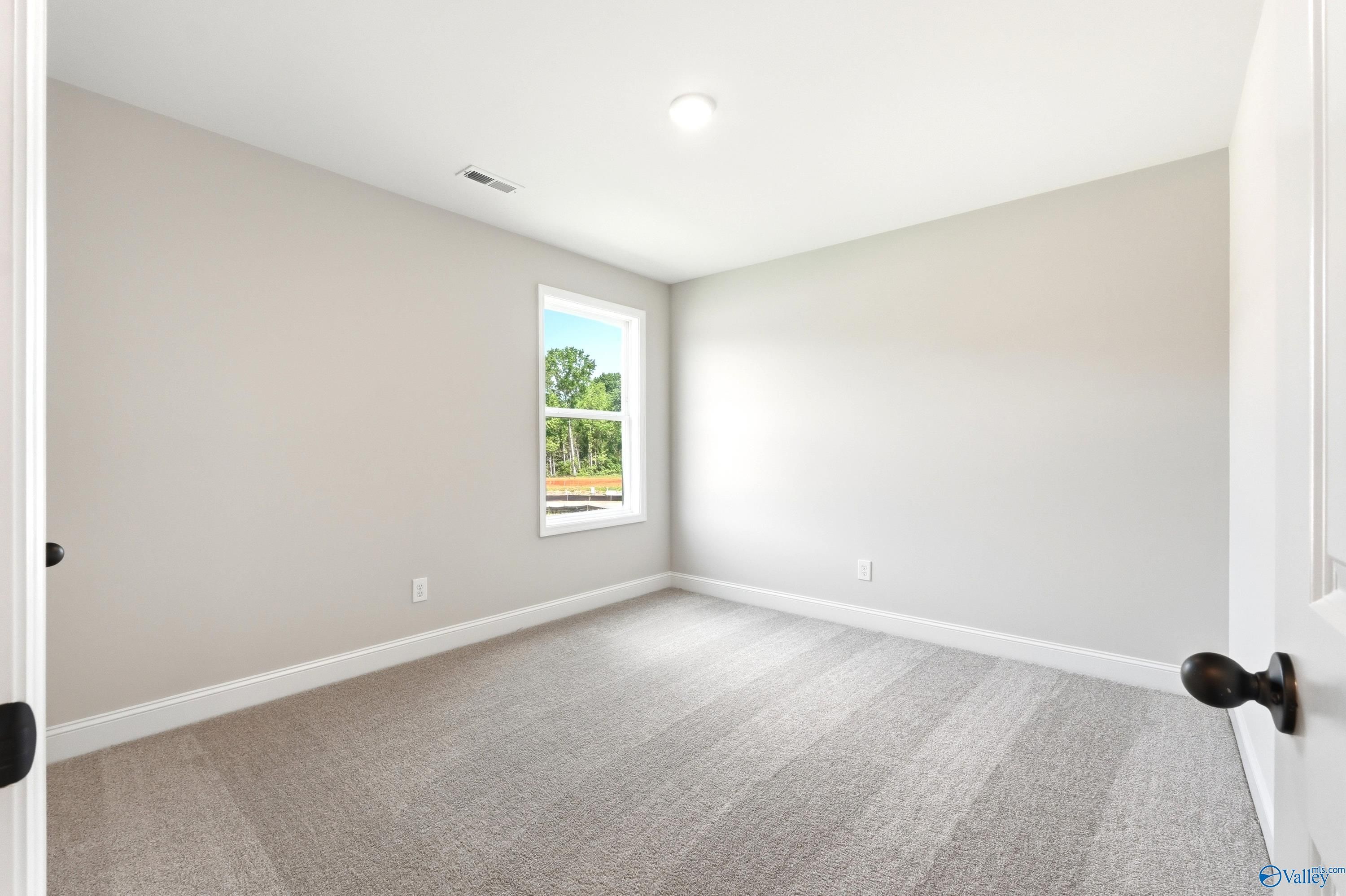 Bright, neutral bedroom with plush carpeting in The Russell A floor plan at Spragins Cove in Huntsville, Alabama.