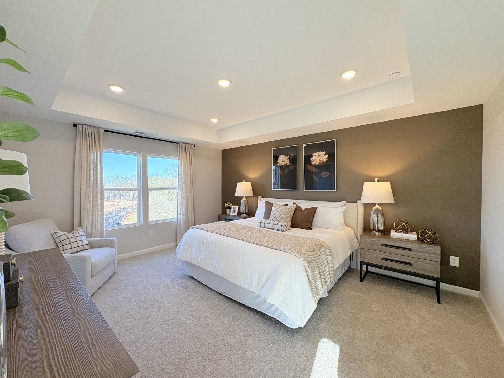 Spacious master bedroom in Hemingway Cumming GA featuring king bed, large windows, neutral walls and plush carpet by Davidson Homes