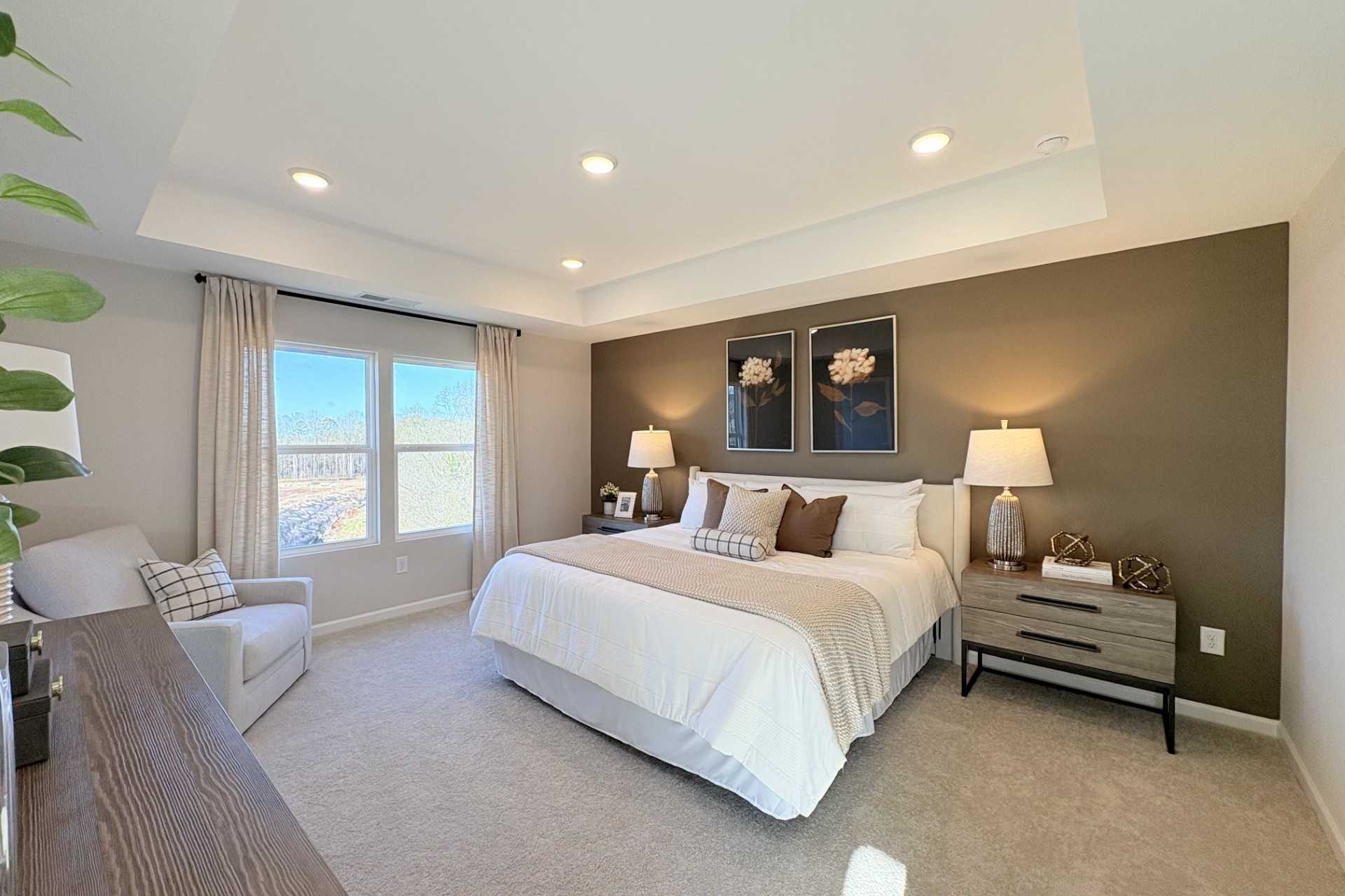 Spacious master bedroom in Hemingway Cumming GA featuring king bed, large windows, neutral walls and plush carpet by Davidson Homes