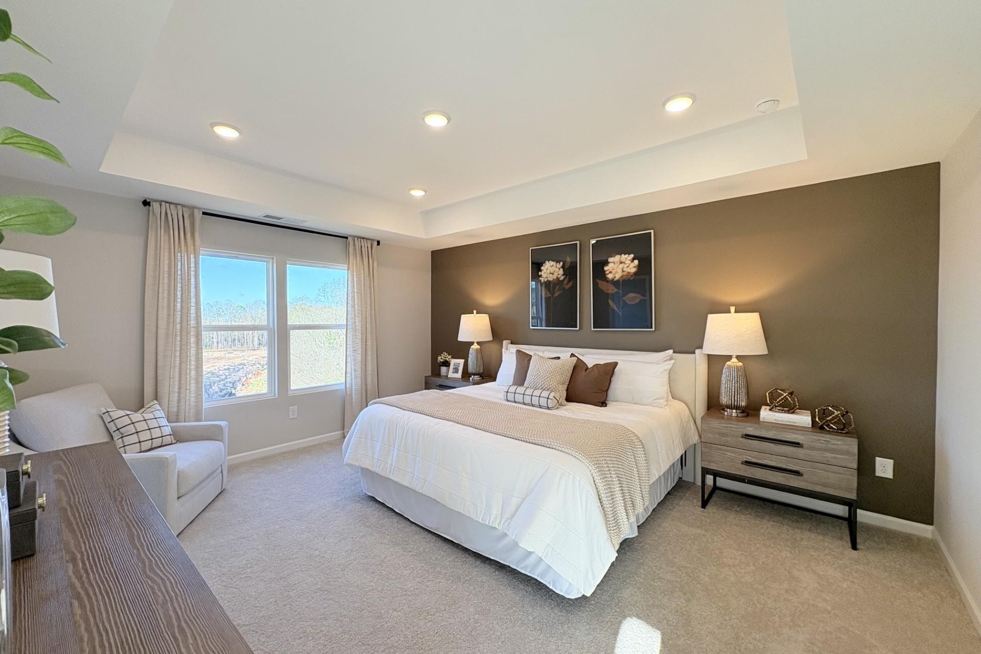 Spacious master bedroom in Hemingway Cumming GA featuring king bed, large windows, neutral walls and plush carpet by Davidson Homes