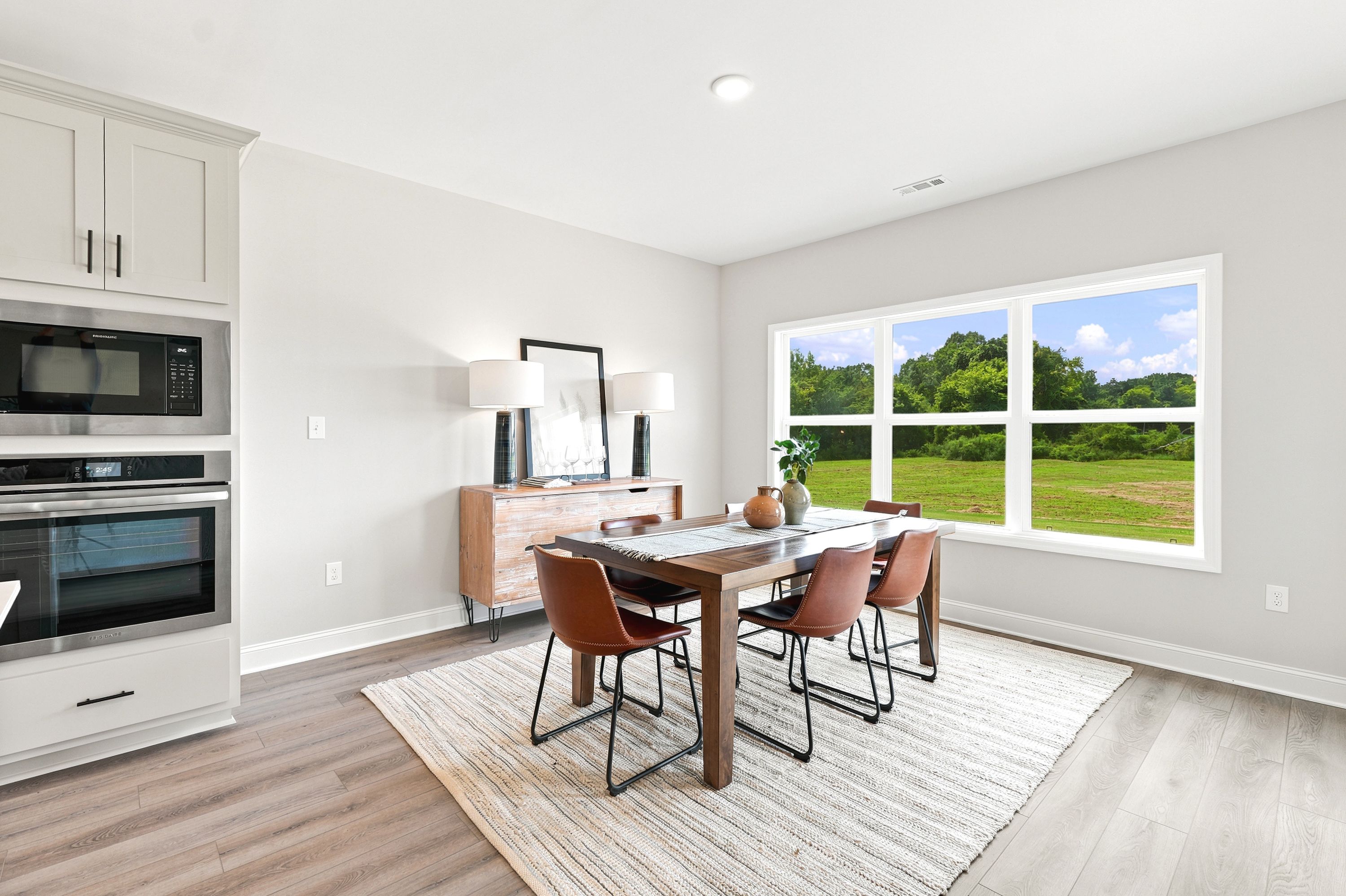 Modern dining area at Riverton Preserve in Huntsville, AL with wood table, leather chairs, and large windows.