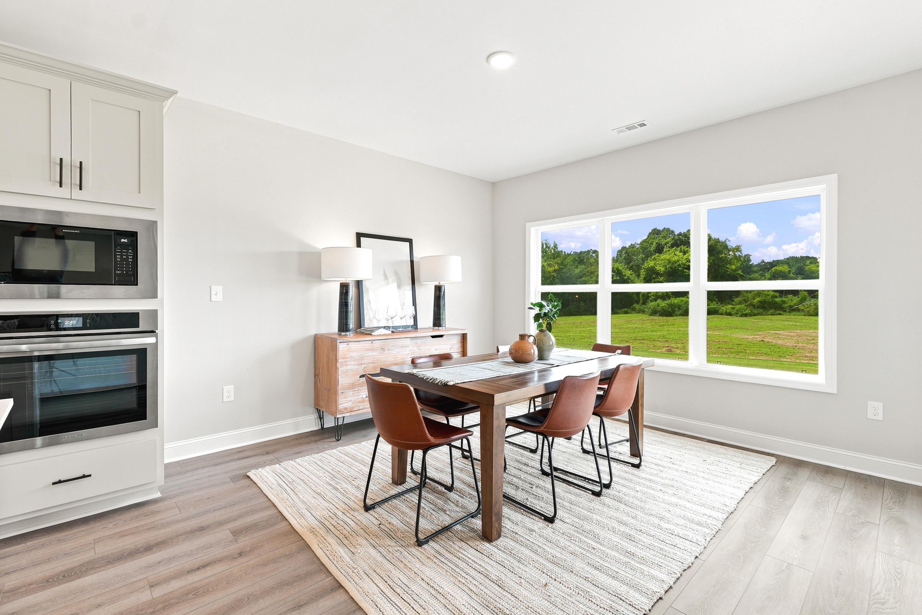 Modern dining area at Riverton Preserve in Huntsville, AL with wood table, leather chairs, and large windows.
