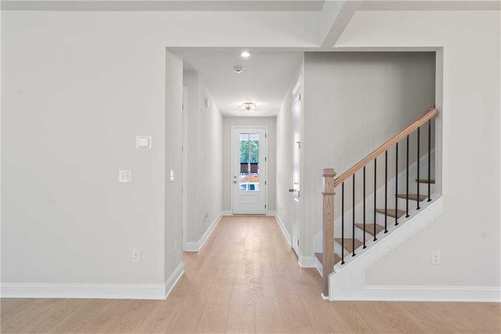 Bright hallway with oak hardwood floors, wooden staircase, and glass French door in Davidson Homes The Hickory B, Buford, Georgia