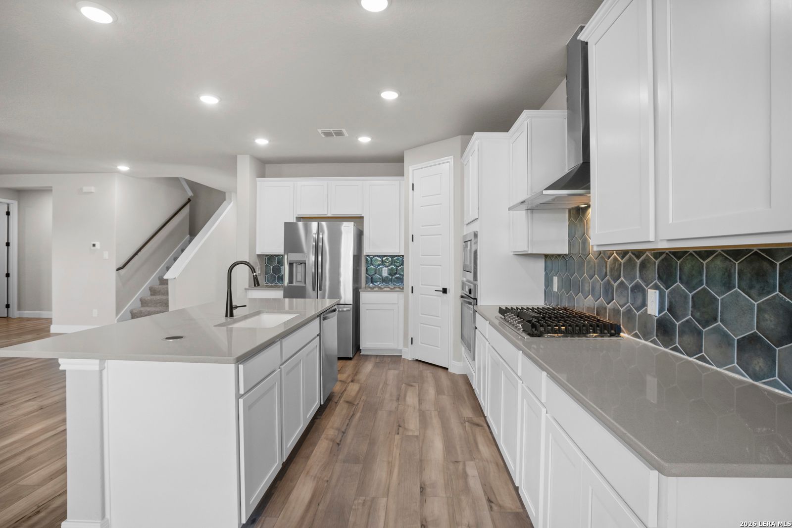 Modern kitchen with white cabinets, quartz countertops, and blue hexagon tile backsplash in The Jennings G floor plan.