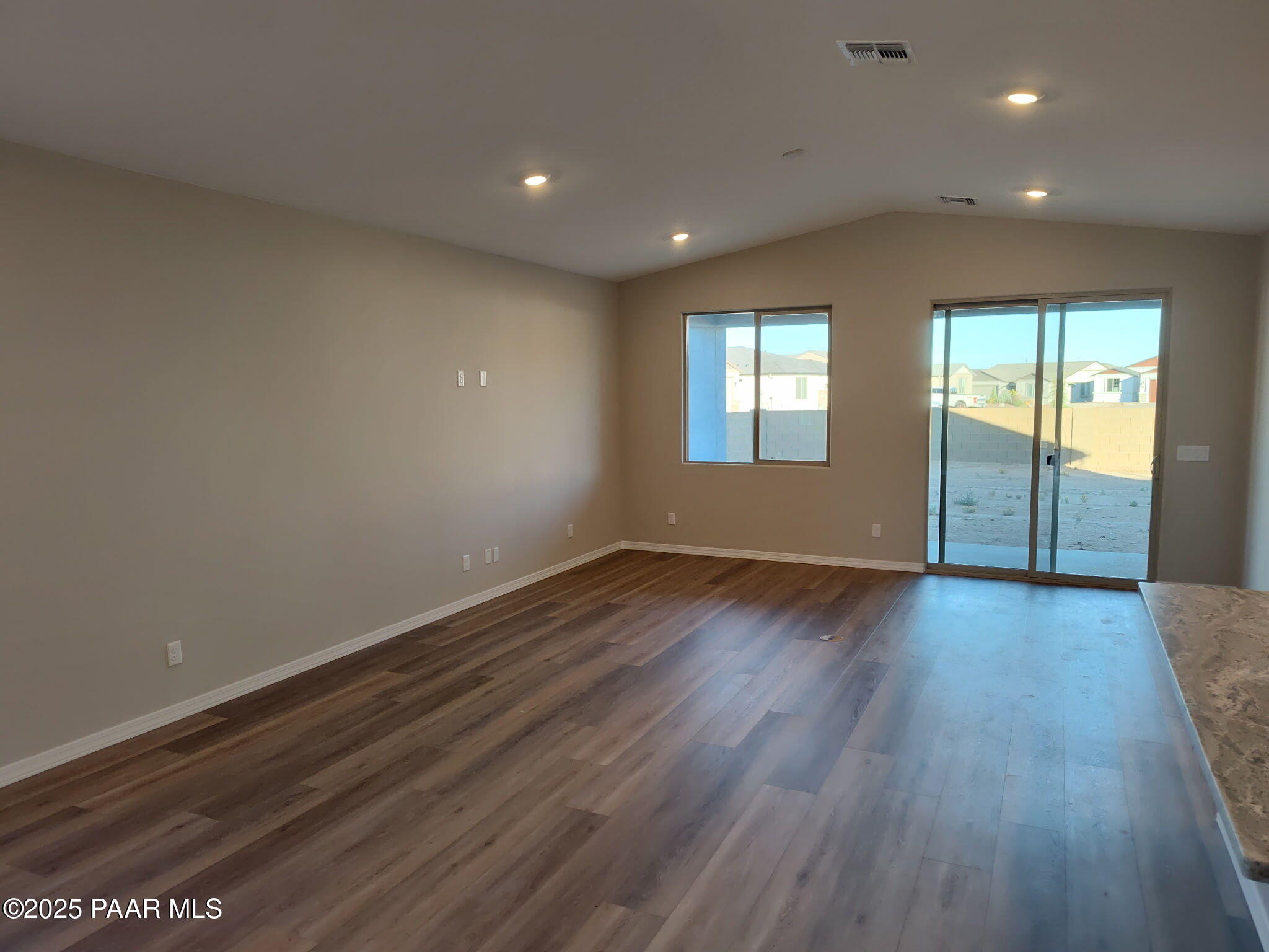 Spacious great room with hardwood floors, sliding glass doors to desert patio, and kitchen island in Davidson Homes The Frontier A, Prescott Valley, AZ