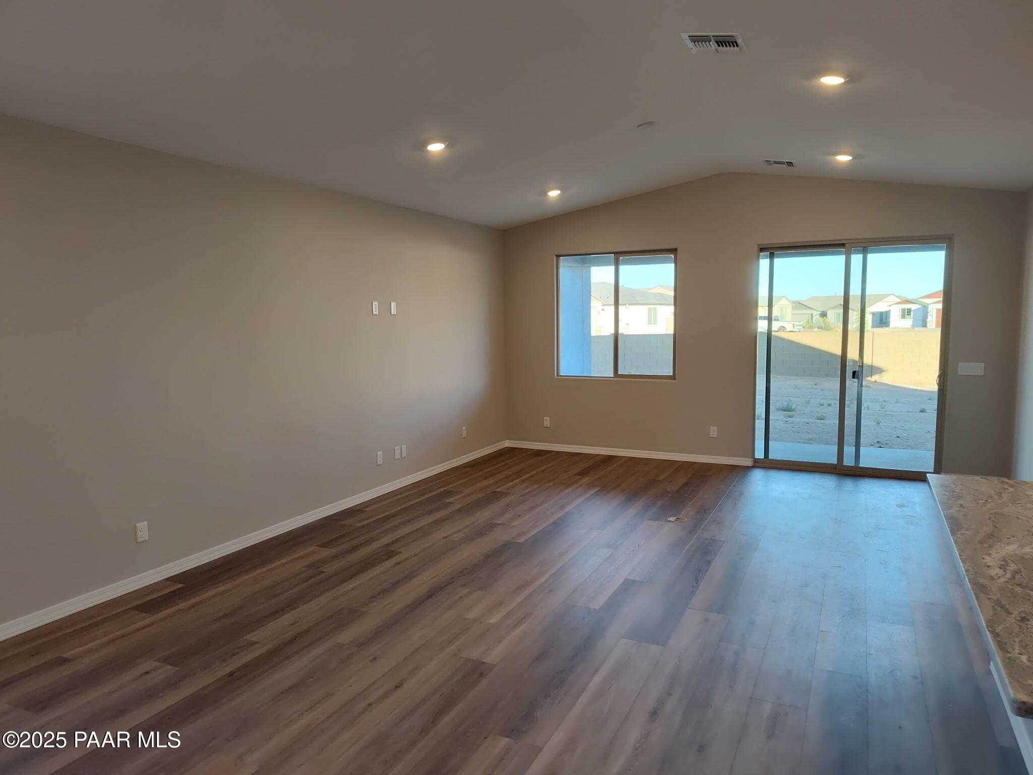 Spacious great room with hardwood floors, sliding glass doors to desert patio, and kitchen island in Davidson Homes The Frontier A, Prescott Valley, AZ