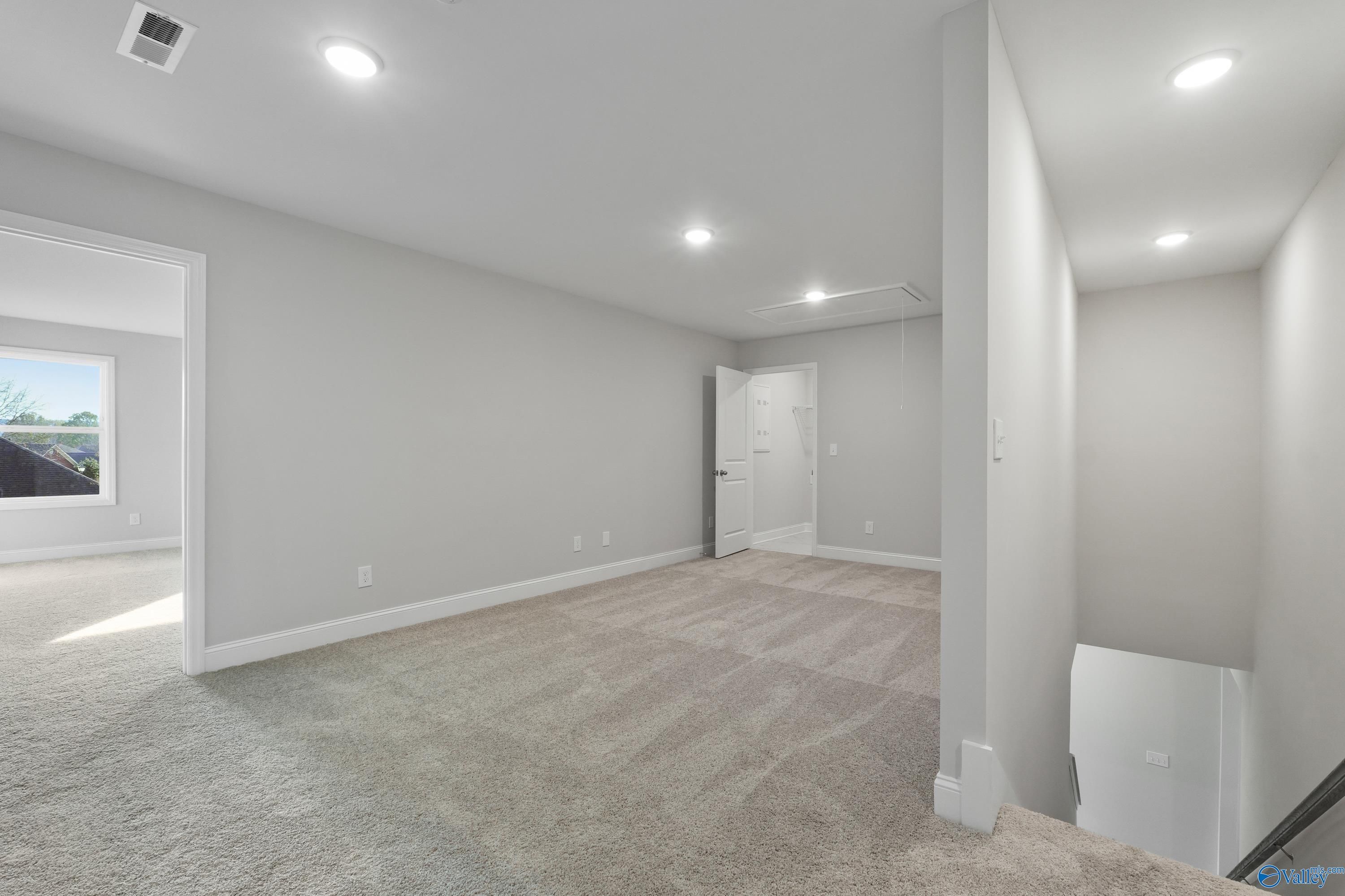 Bright upstairs hallway with gray walls, recessed lights, carpet flooring, and stair access in The Camden B home, Huntsville AL