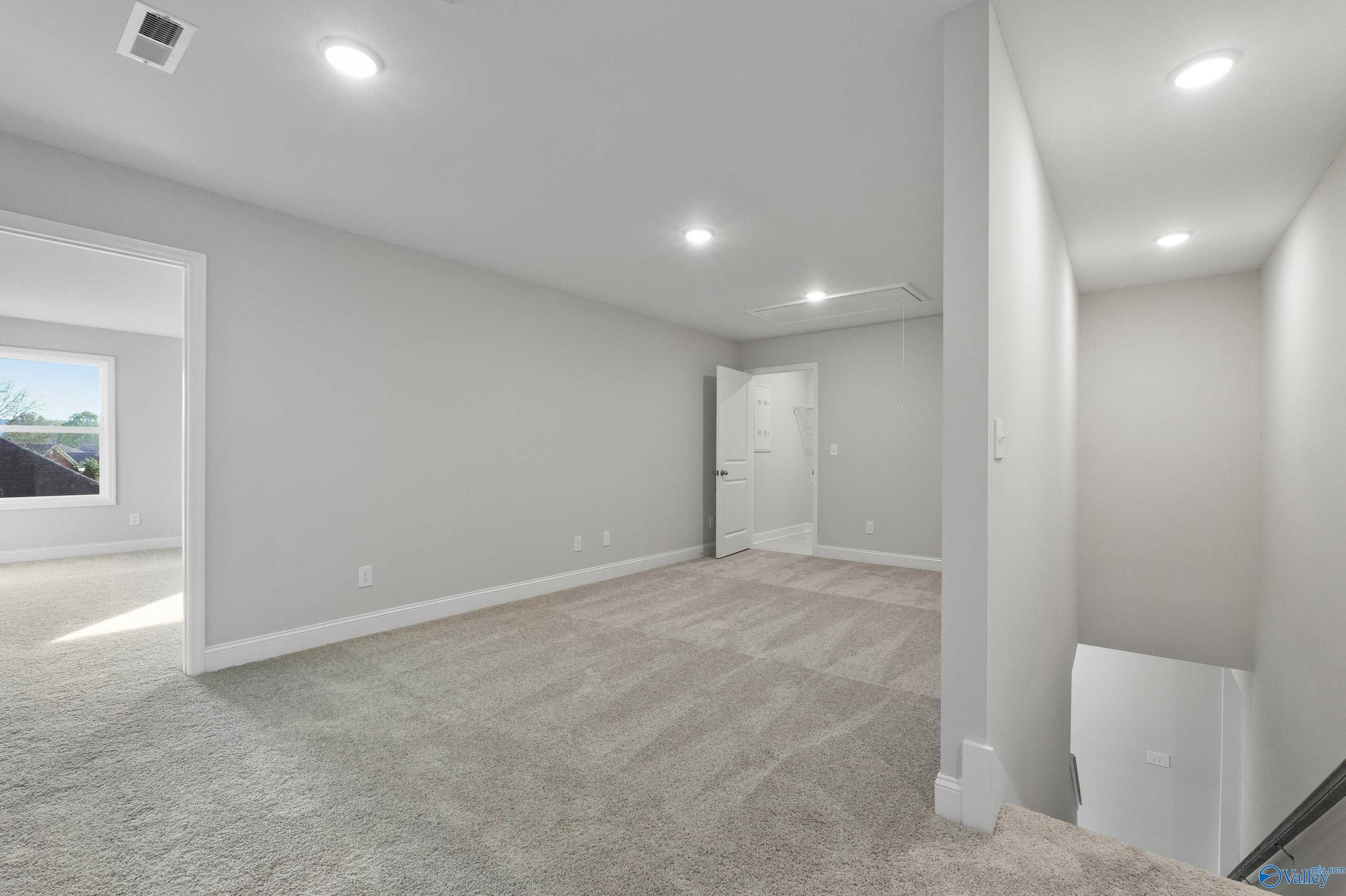 Bright upstairs hallway with gray walls, recessed lights, carpet flooring, and stair access in The Camden B home, Huntsville AL