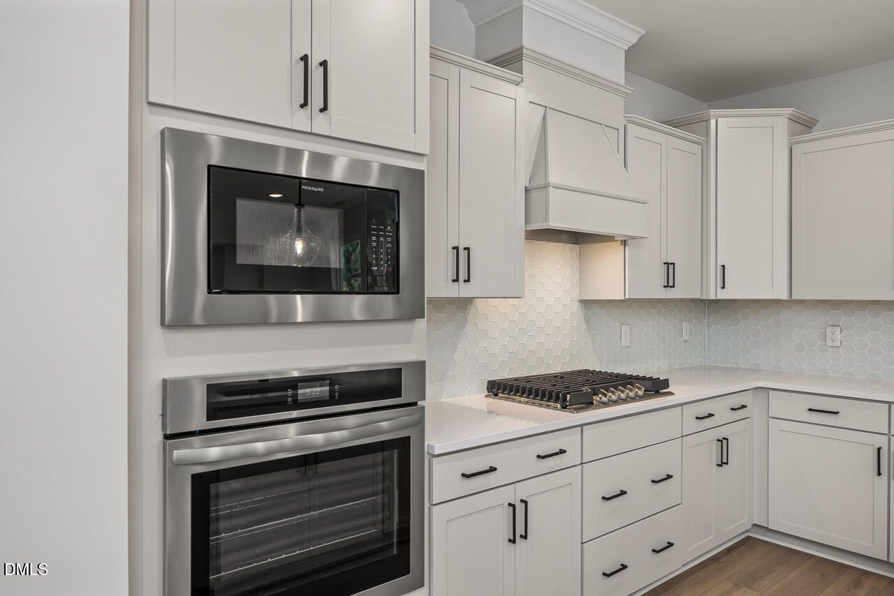 Modern kitchen with stainless steel oven, microwave, and gas cooktop in The Birch II E home at Sage on North Main.